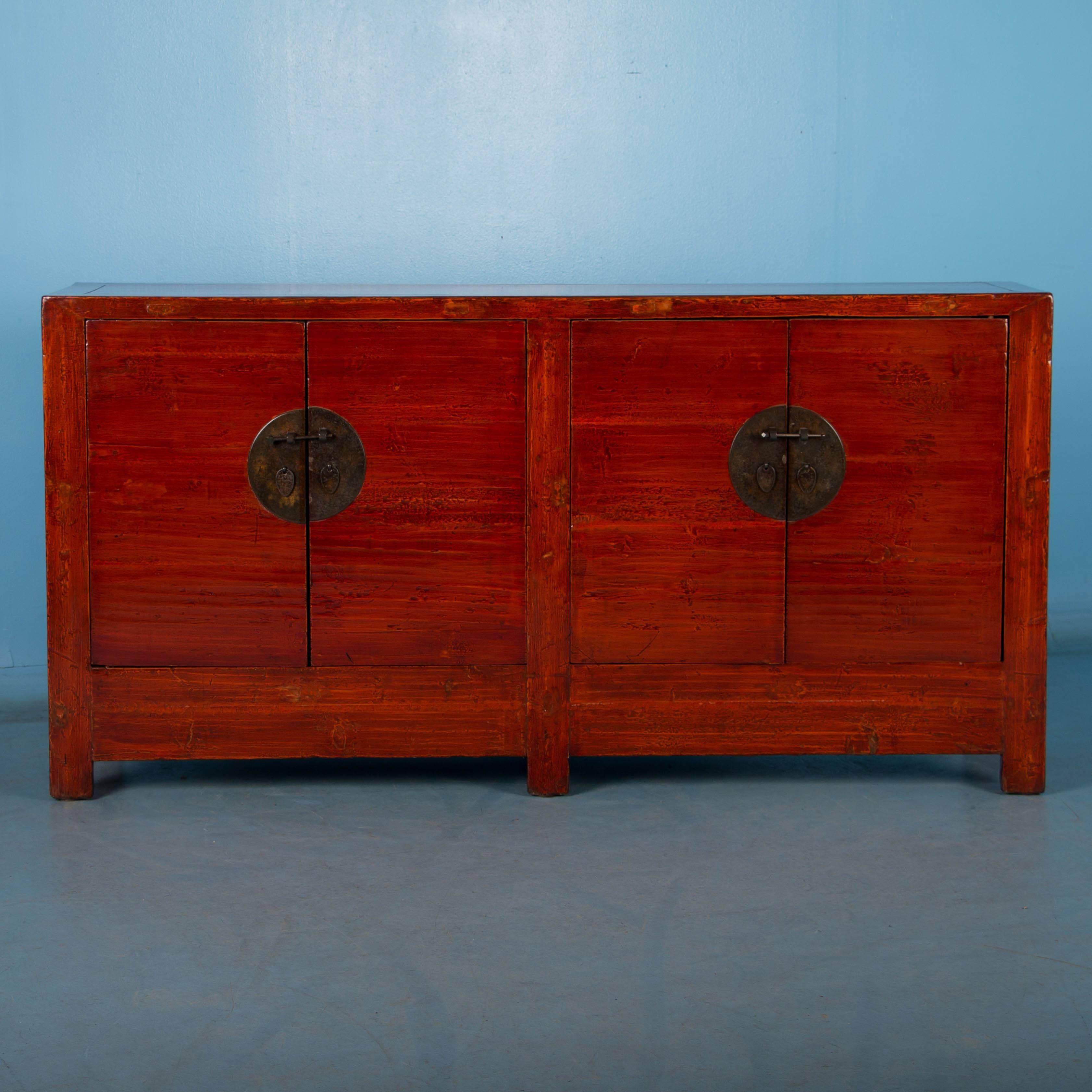 The rich red color of this pine four-door cabinet absolutely glows with it's highly polished lacquered finish, enhancing the old layers of paint in lighter and darker shades of red underneath. The black painted interior offers a nice contrast and