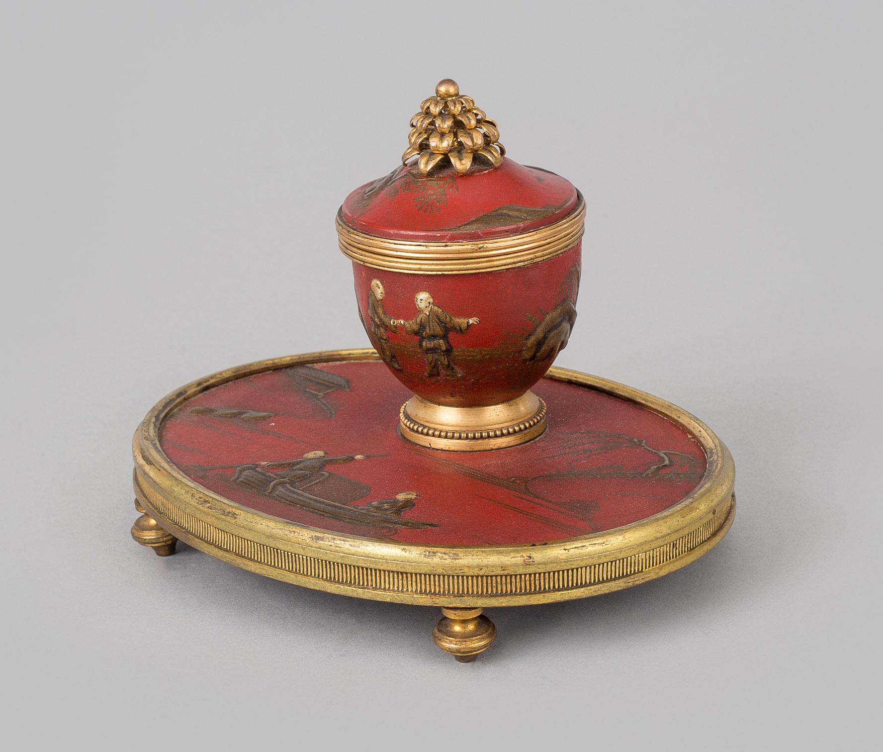 Charming small oval gilded bronze red lacquered chinoiserie inkstand with hinged top revealing the ink receptacle inside, mounted on small gilded feet.