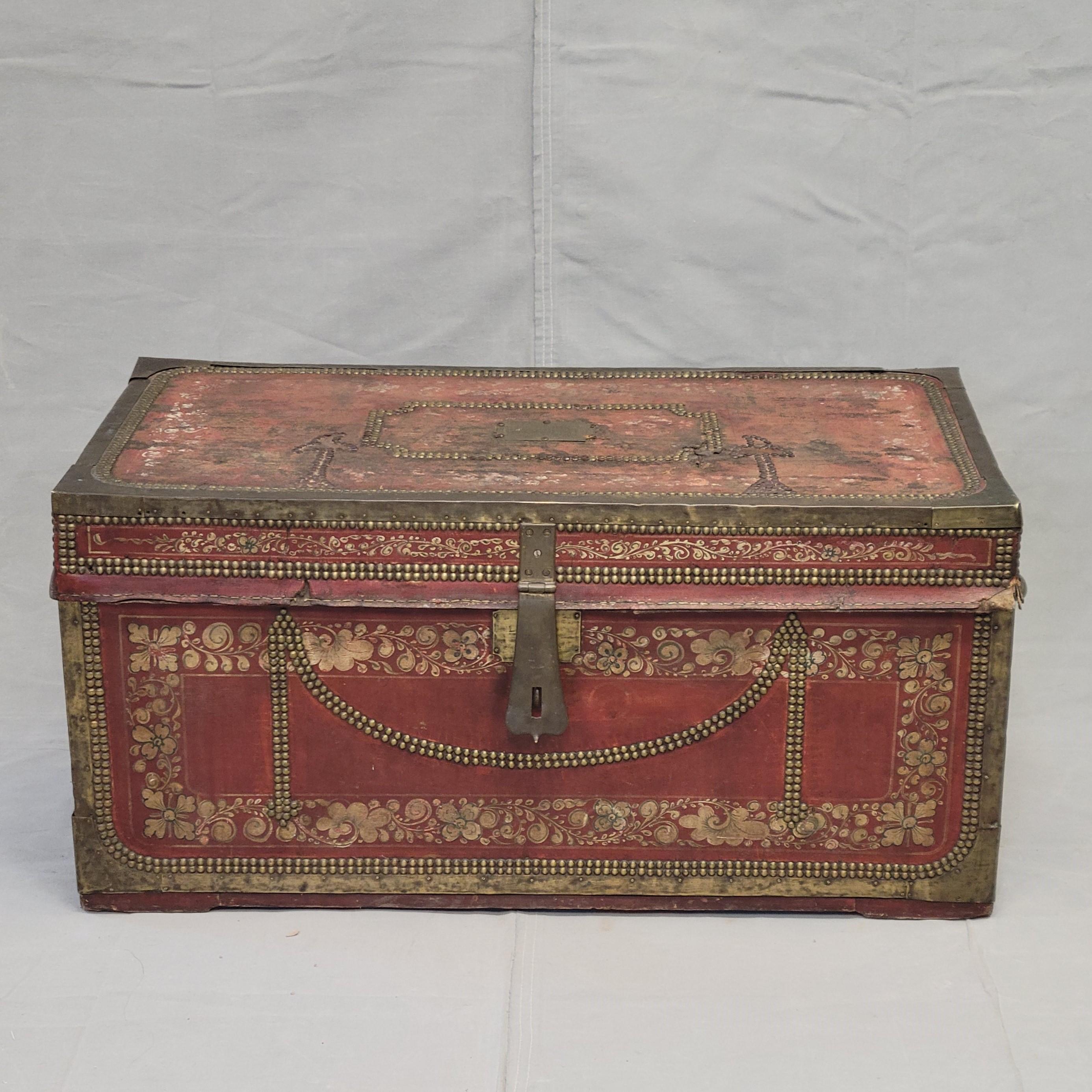 A beautiful, antique (mid 1800s) Chinese red leather and brass over camphor wood export trade trunk offers ample storage and could be used as a coffee table or accent piece. It is a gorgeous, rich red color with cream colored floral painted accents