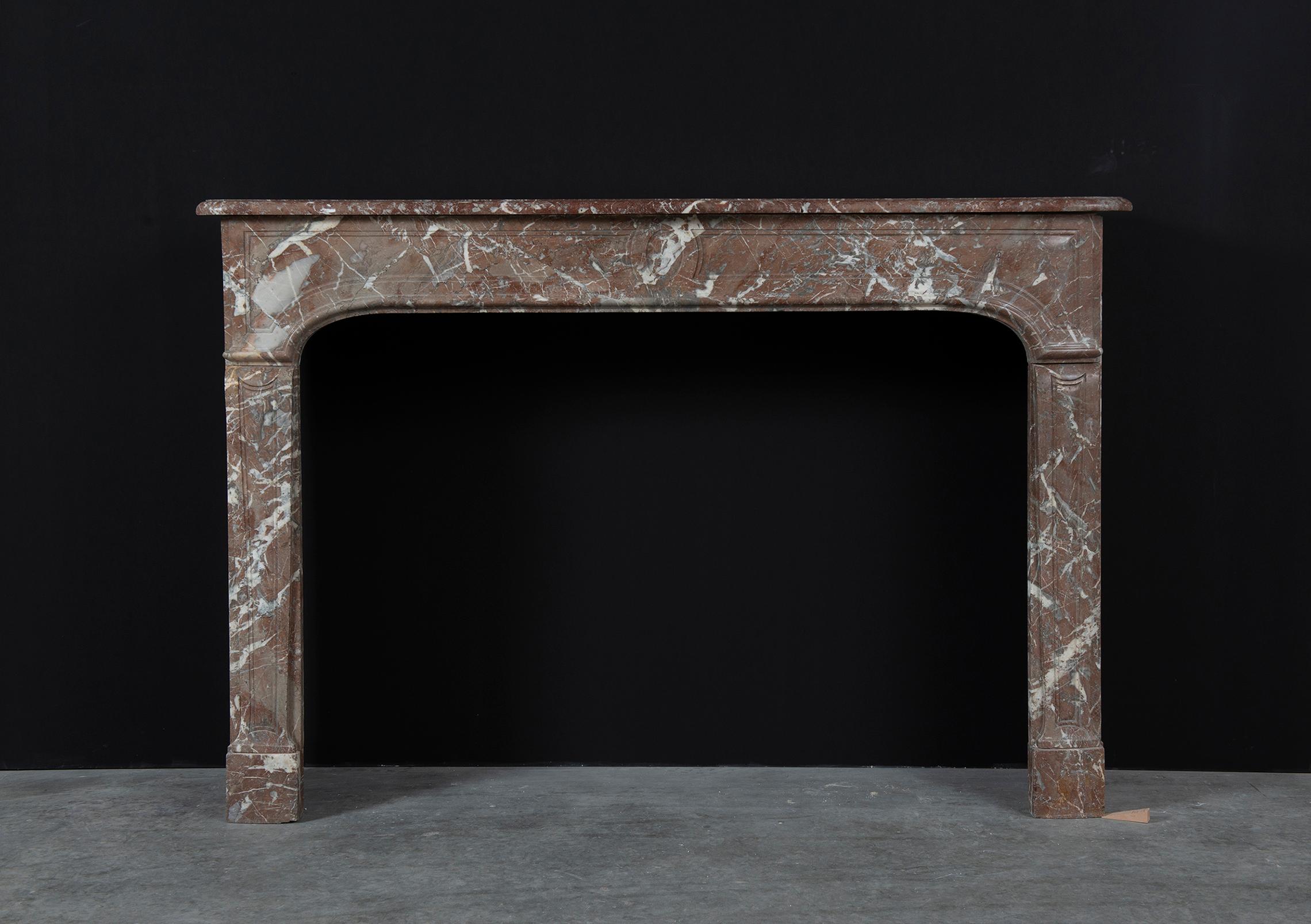 Lovely Belgium red marble fireplace mantel.
This very elegant mantel has a beautiful shaped and profiled topshelf above a shallow paneled frieze. Supported by to tapering paneled jambs with curved enblocks. The sides are the same depth as the