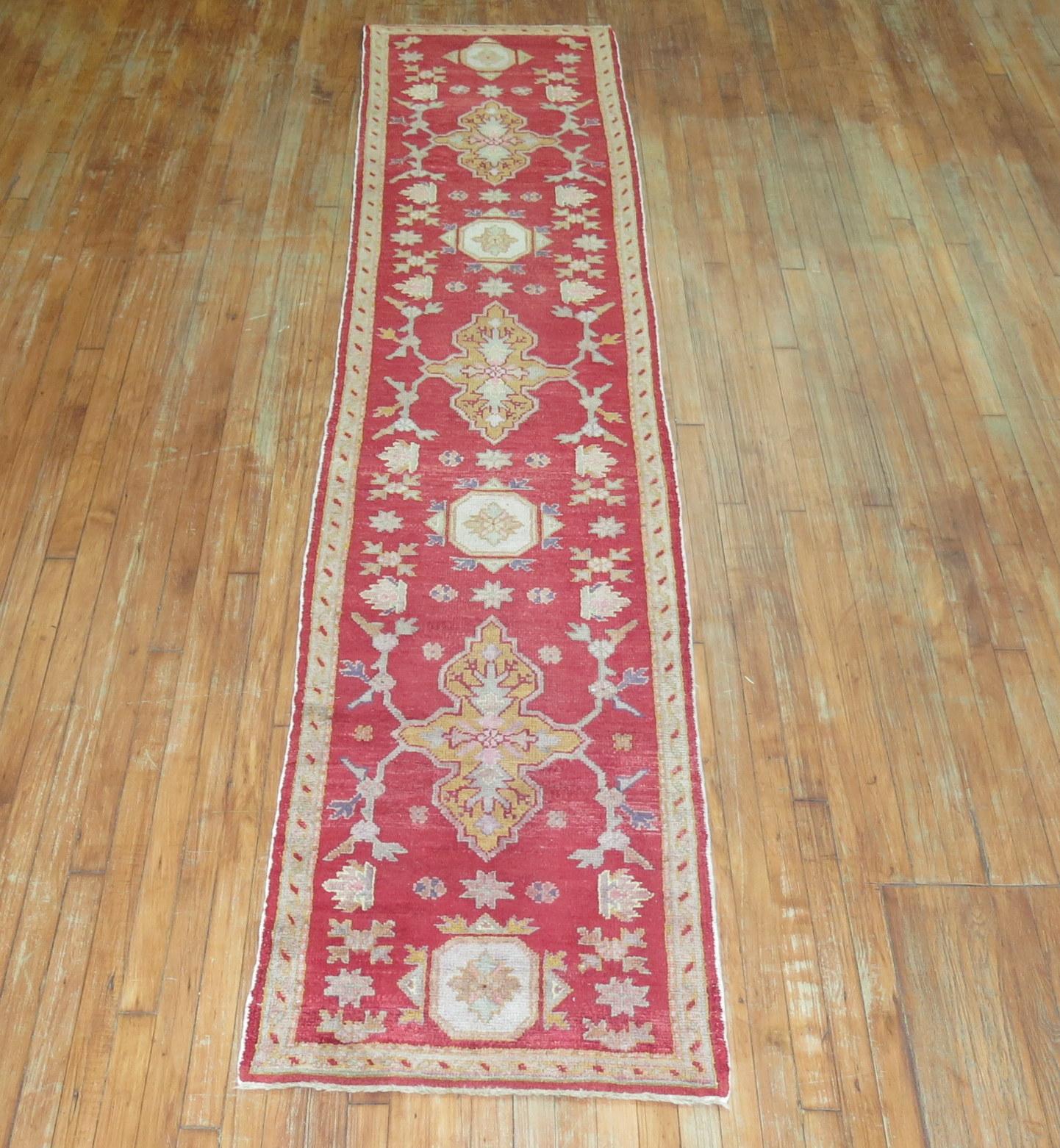 Antique Turkish Oushak runner with multiple medallions on a bright red field.