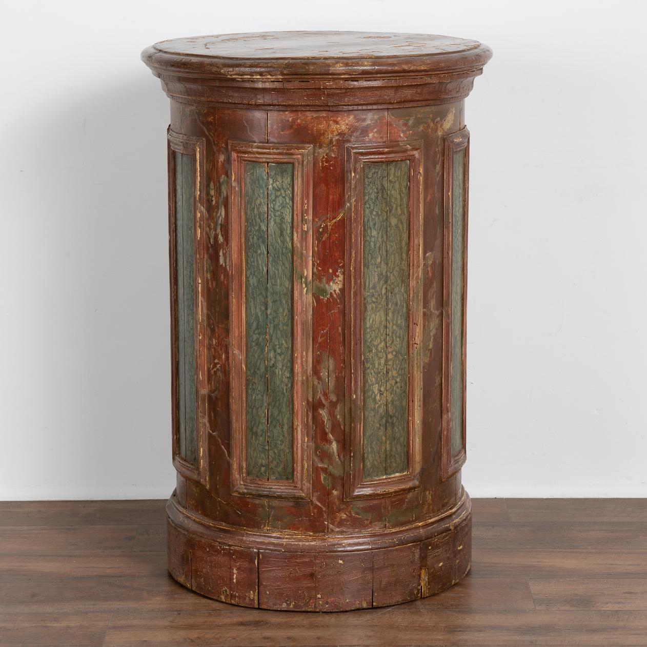 This round, hand-painted wood pedestal from Sweden is an exceptional find due to the highly original painted finish. 
A brick red background is complimented by a blue-green faux marble finish inside the paneled accents.
Restored and waxed, this