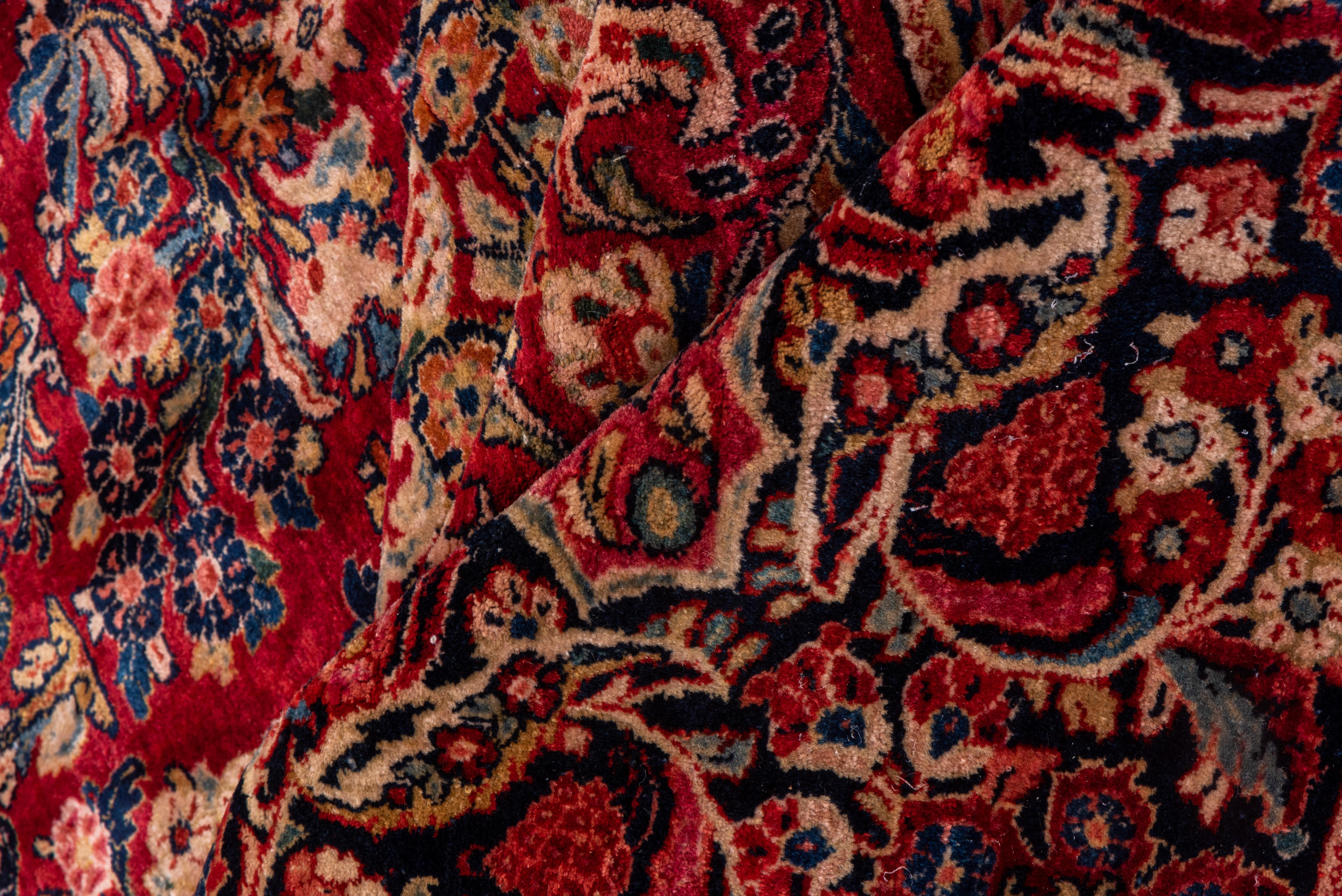 Detached floral sprays swim busily on the red ground, carefully skirting the small central motif. This is a classic 