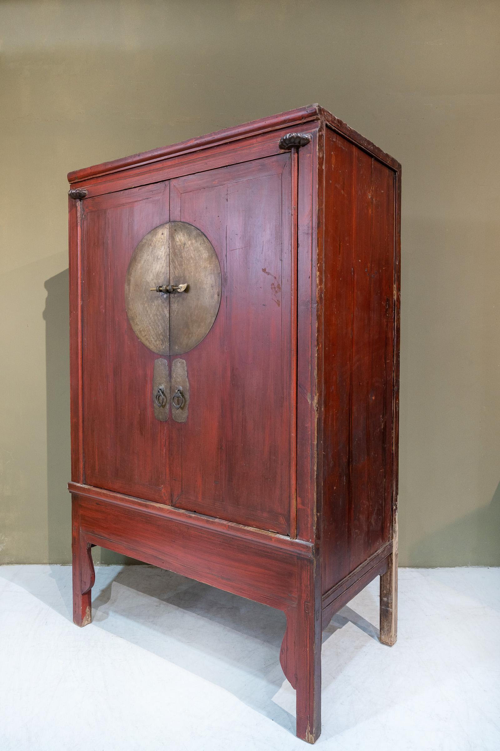 An antique red wedding cabinet from Zhejiang province, China. This piece has beautiful original red colour and patina, and its original brass hardware. Typically, such cabinets have their framework made of Elm, and the insides of the cabinet, back