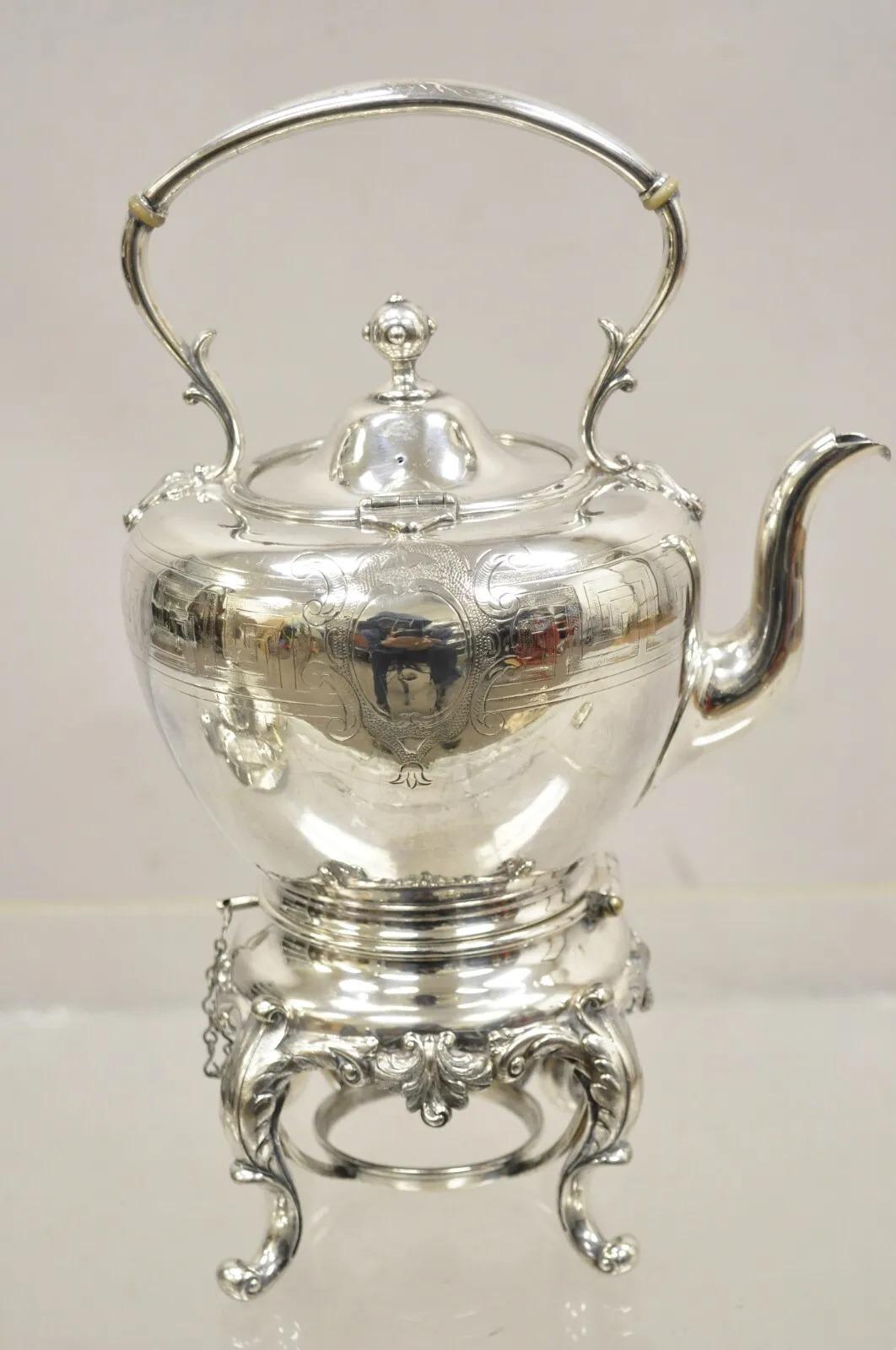 Antique Reed & Barton 1866 Silver Plated Victorian Tilting Tea Pot on Stand. Item features shield and greek key design, scrolling footed base, original hallmark. Circa Early to Mid 20th Century. Measurements:  13