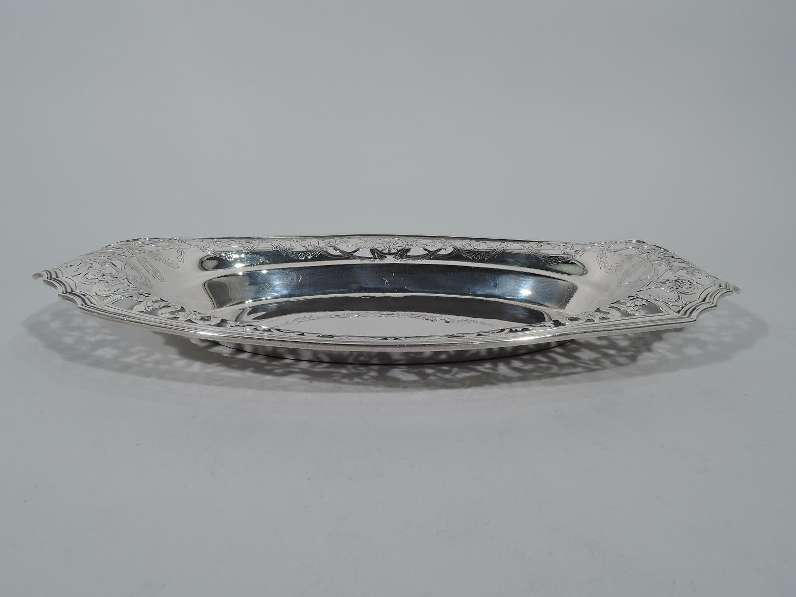 Edwardian sterling silver bread tray. Made by Reed & Barton in Taunton, mass, solid oval well bordered by pierced scrolls, ribbon, flowers, and paterae. Shaped and molded rim. Hallmark includes pattern no. 339AE. Measures: Weight 11.8 troy ounces.