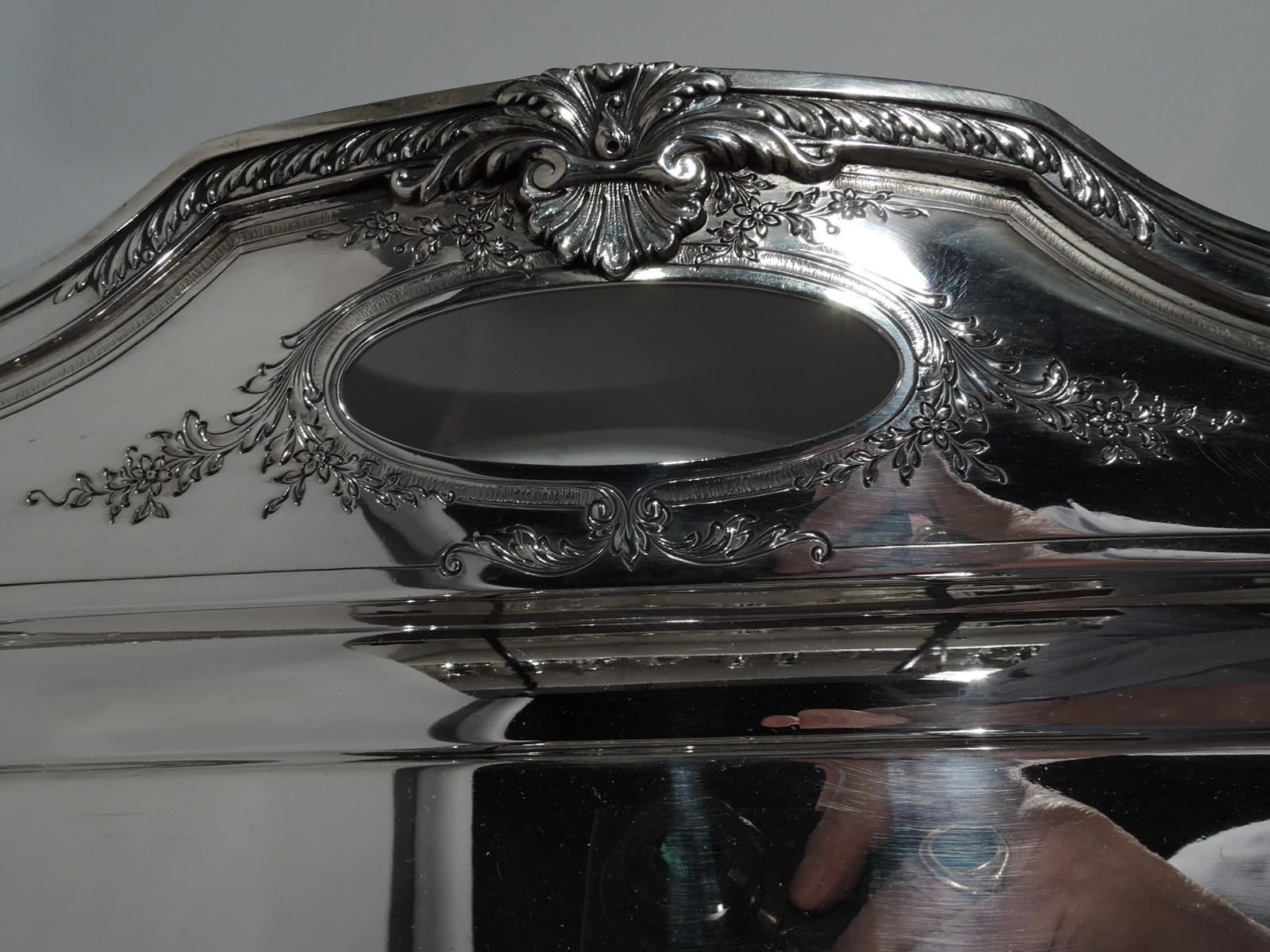 Edwardian sterling silver tea tray in Heritage pattern. Made by Reed & Barton in Taunton, Mass., circa 1925. Rectangular well with curved corners, flat shoulder, chamfered corners and shaped ends with cutout oval handles. Chased and applied