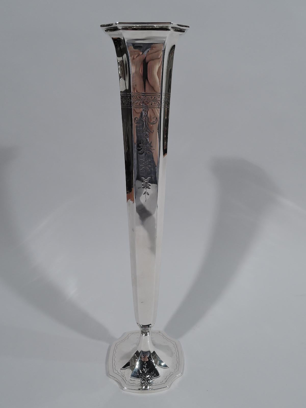 Tall Edwardian sterling silver vase. Made by Reed & Barton in Taunton, Mass., circa 1915. Narrow and quadrilateral with concave corners. Engraved floral border with pendant flowers. Foot raised, faceted, and concave with engraved scalloped border