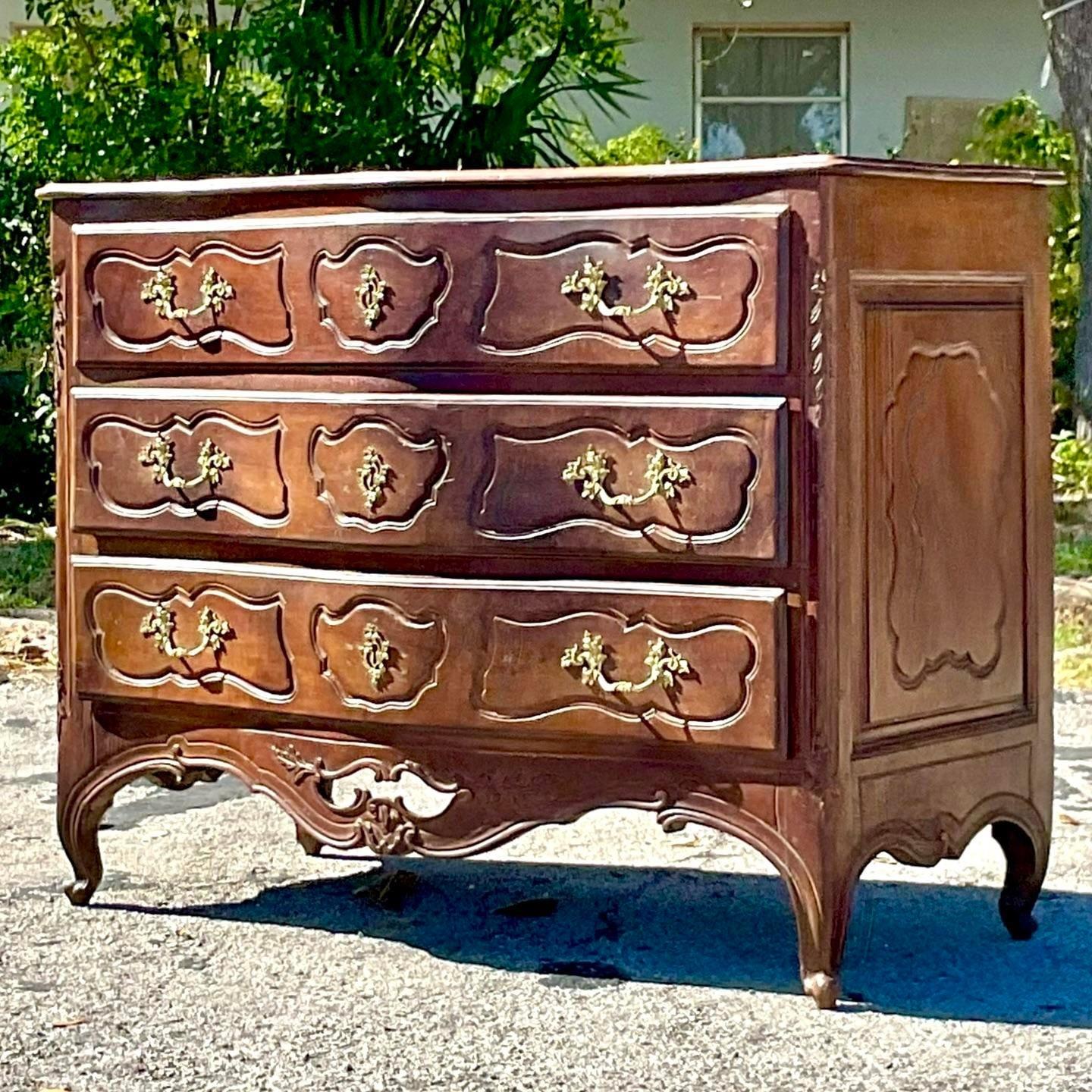 A stunning vintage Regency chest of drawers. A beautifully carved heavy Walnut cabinet with gorgeous brass hardware. Lots of great patina from time. Acquired from a Palm Beach estate.