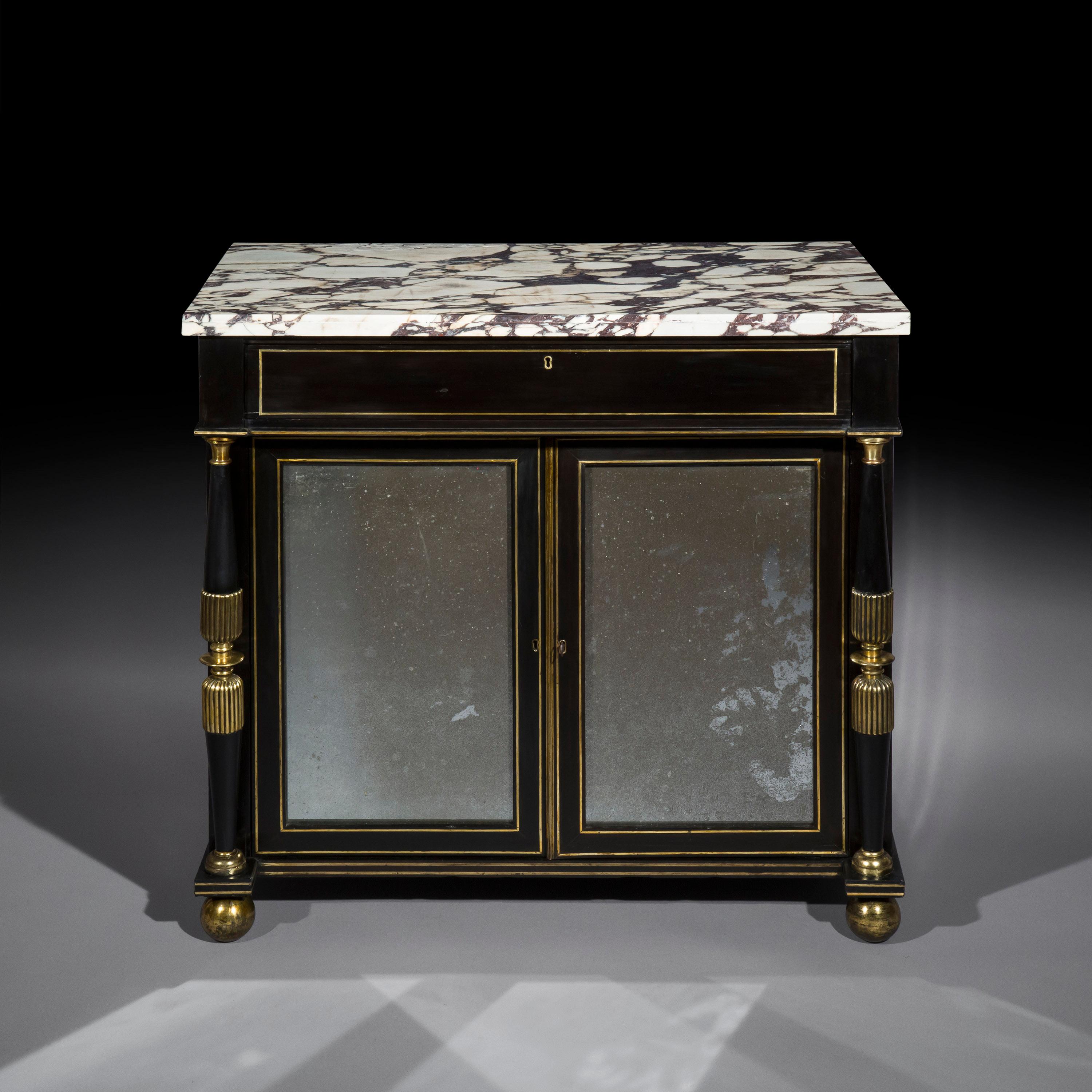 Ein sehr dekorativer Schrank aus der Regency-Periode, ebonisiert, mit Messingeinlagen und Ormolu, mit Spiegeltüren und einer Platte aus Calacatta-Viola-Marmor, in der Art von James Newton.
Englisch, um 1815

Warum wir es mögen
Eines der elegantesten