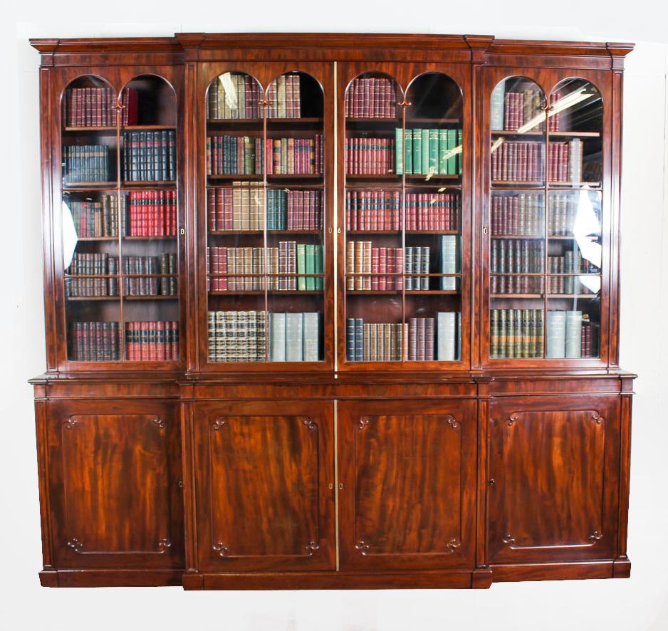 A superb antique English Regency period top quality flame mahogany four door breakfront bookcase, masterfully crafted in rich solid mahogany, circa 1820 in date.
This magnificent bookcase features a molded breakfront cornice over four double-arched