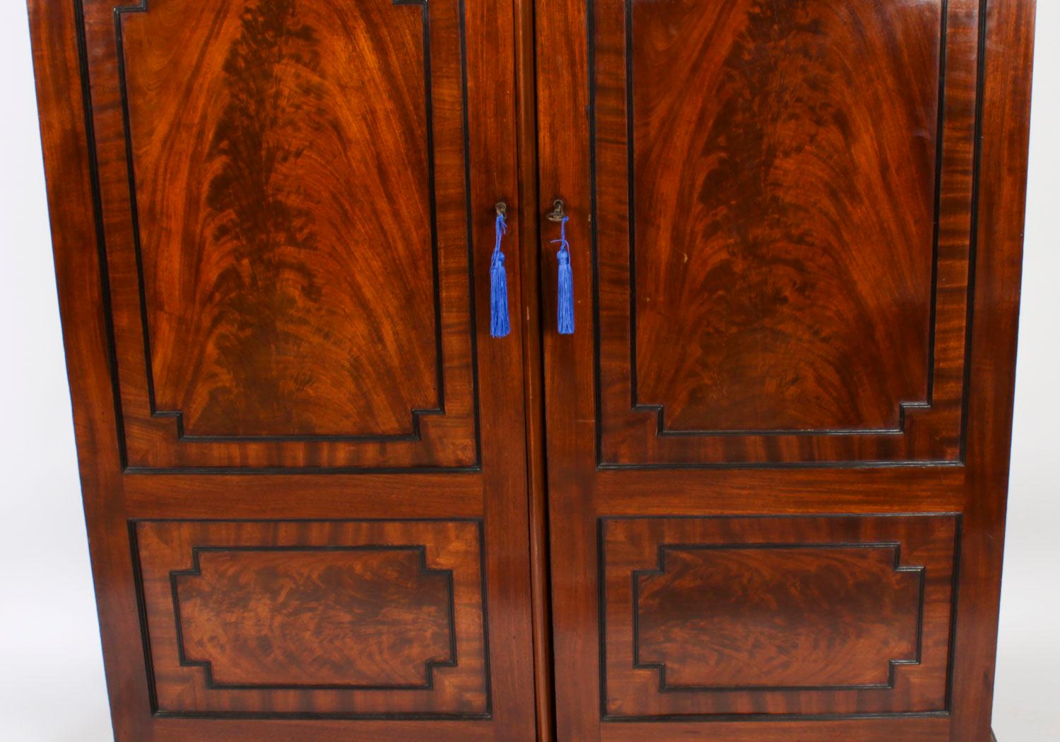Il s'agit d'une impressionnante et élégante armoire pour homme en acajou flammé de style Régence anglaise, à la manière de Marsh & Tatham, datant d'environ 1815.

Cette magnifique armoire haute à deux portes présente une corniche exquise avec des