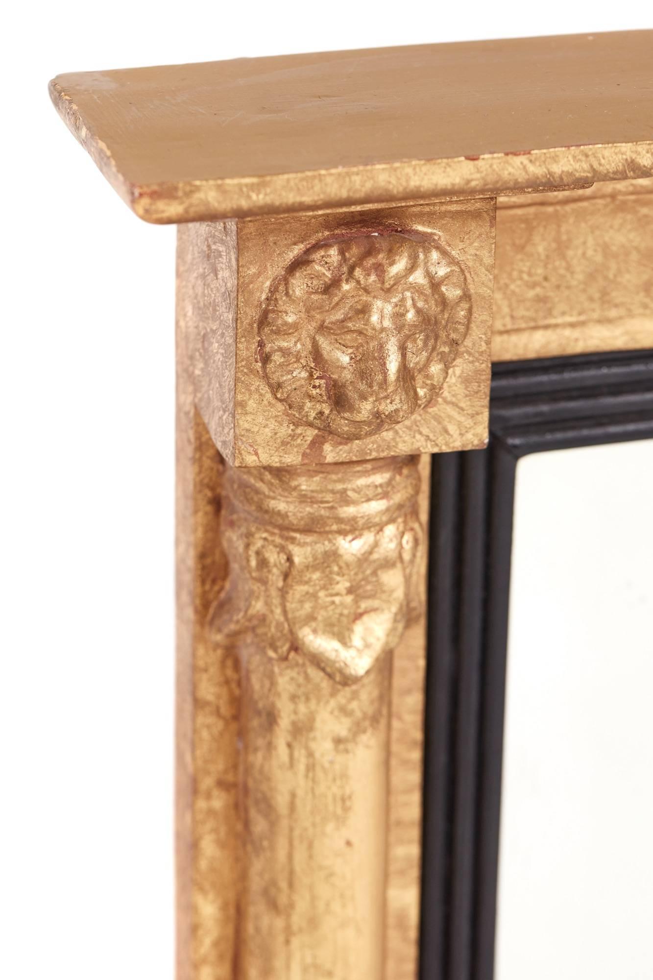 Antique Regency gilt overmantel mirror, gilt frieze with lion head motifs, split columns, ebonized and reeded dividers to the original plate mirror, standing on original ebonized ball feet
Lovely condition.