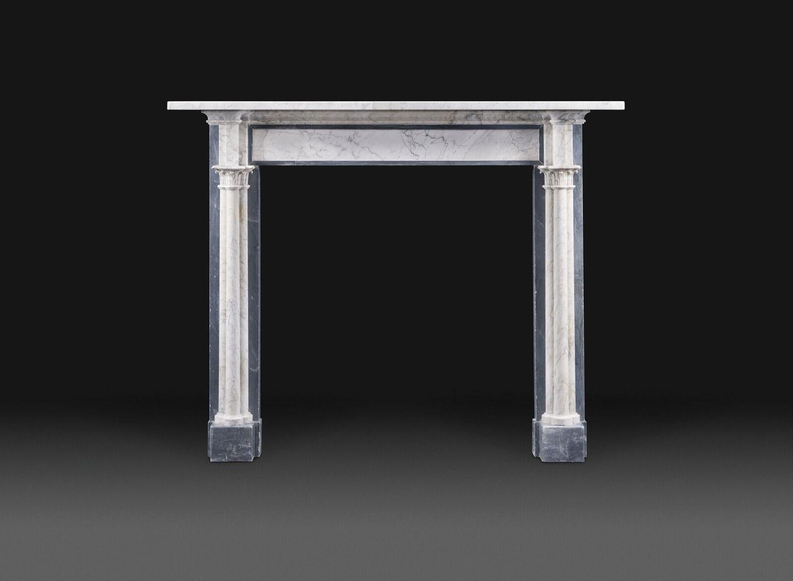 An early 19th century, Regency Gothic Revival chimneypiece in grey and veined white marbles, with simple rectangular shelf and panelled frieze inset with grey. The jambs in the form of three clustered columns with foliate capitals, with clustered