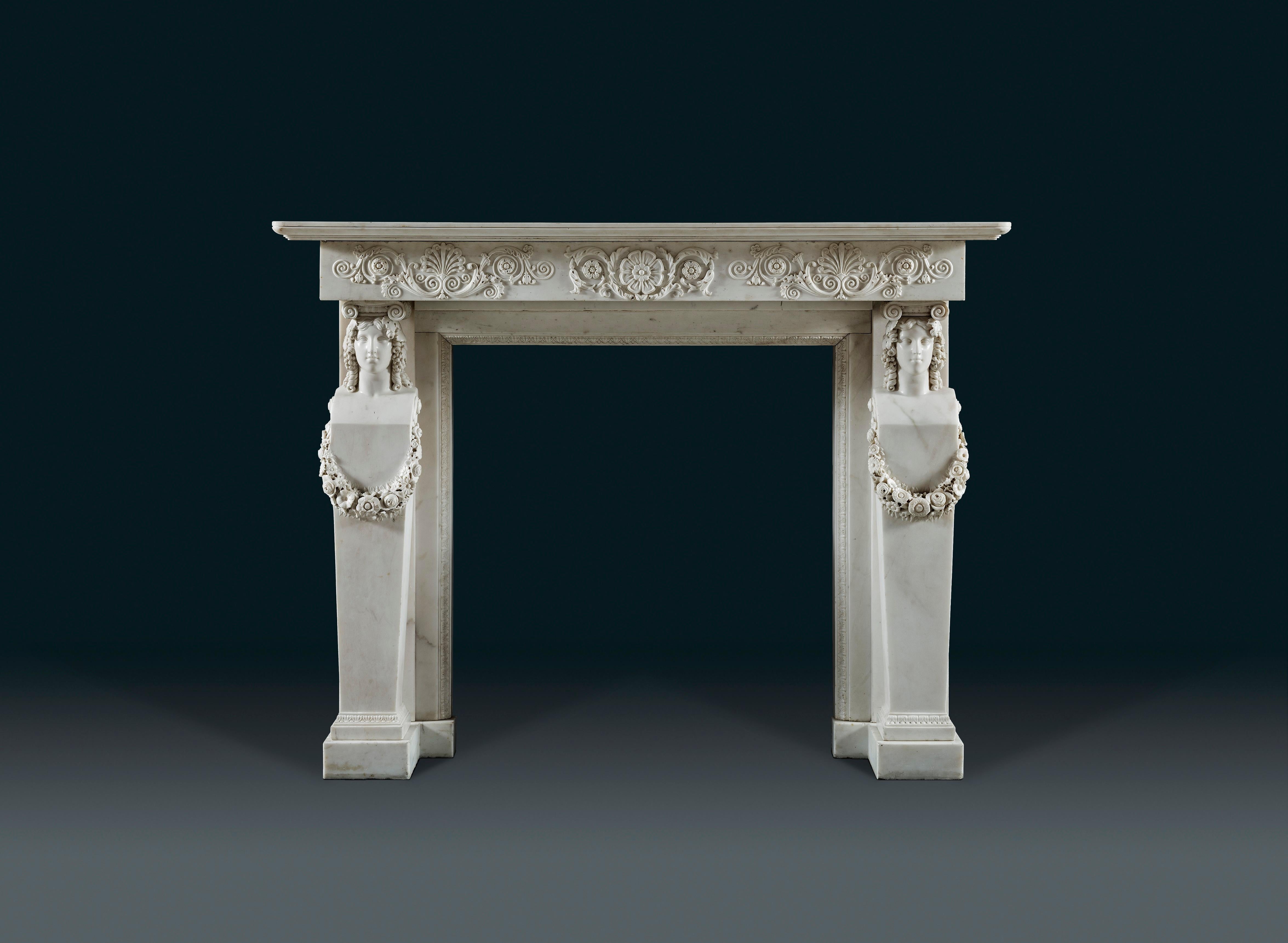 A good early 19th century, Regency, Greek Revival, carved statuary marble chimneypiece. The deep shelf with rounded corners and a stepped moulding, above a frieze carved with large anthemion issuing foliate scrolls with flowerhead paterae, raised on