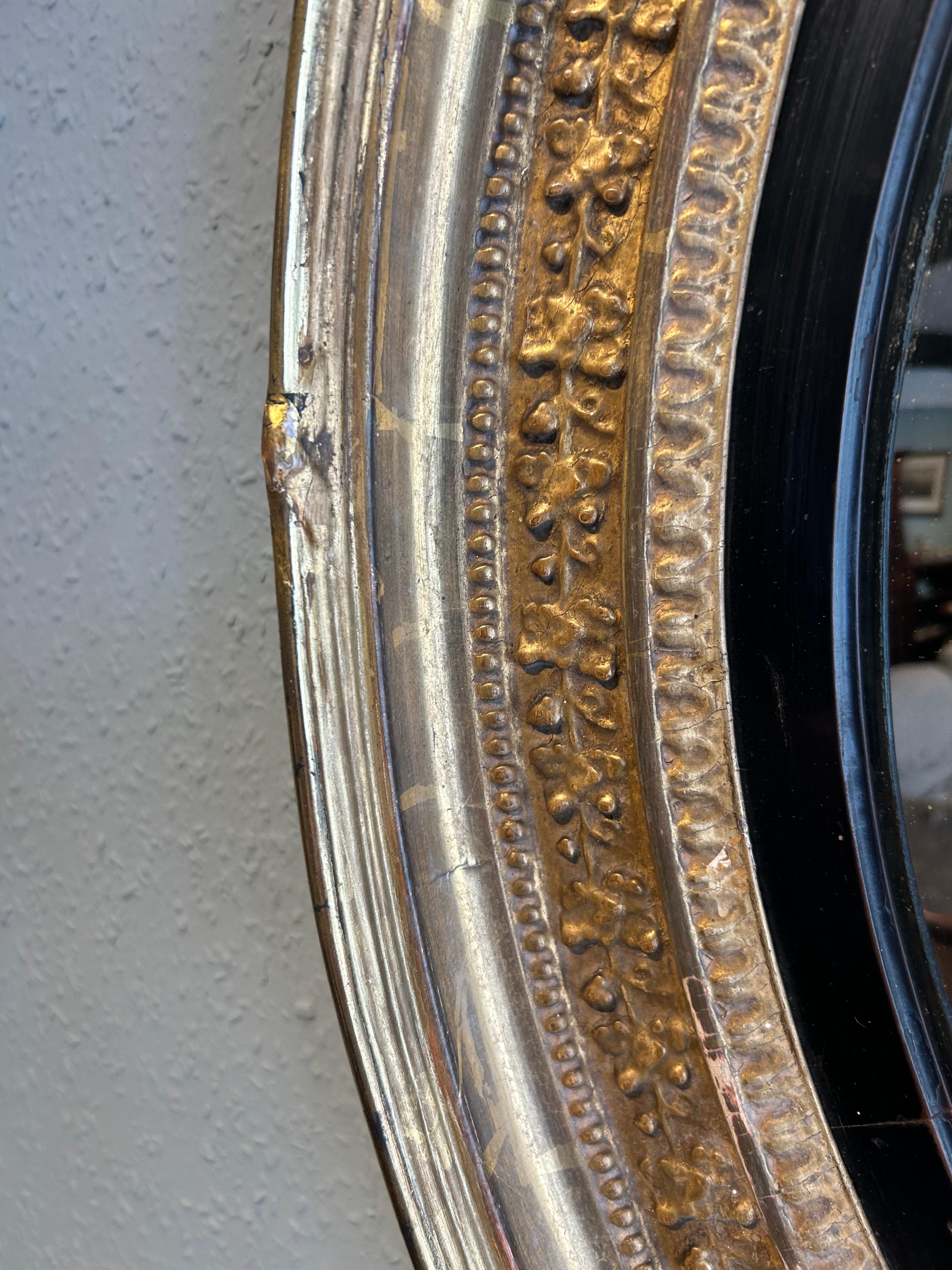 Regency gilt convex mirror of large proportions  with original slightly worn gilding ,being 32 inches diameter with its original convex mirror plate, surrounded by an ebony slip with carved gilded foliage to the perimeter.