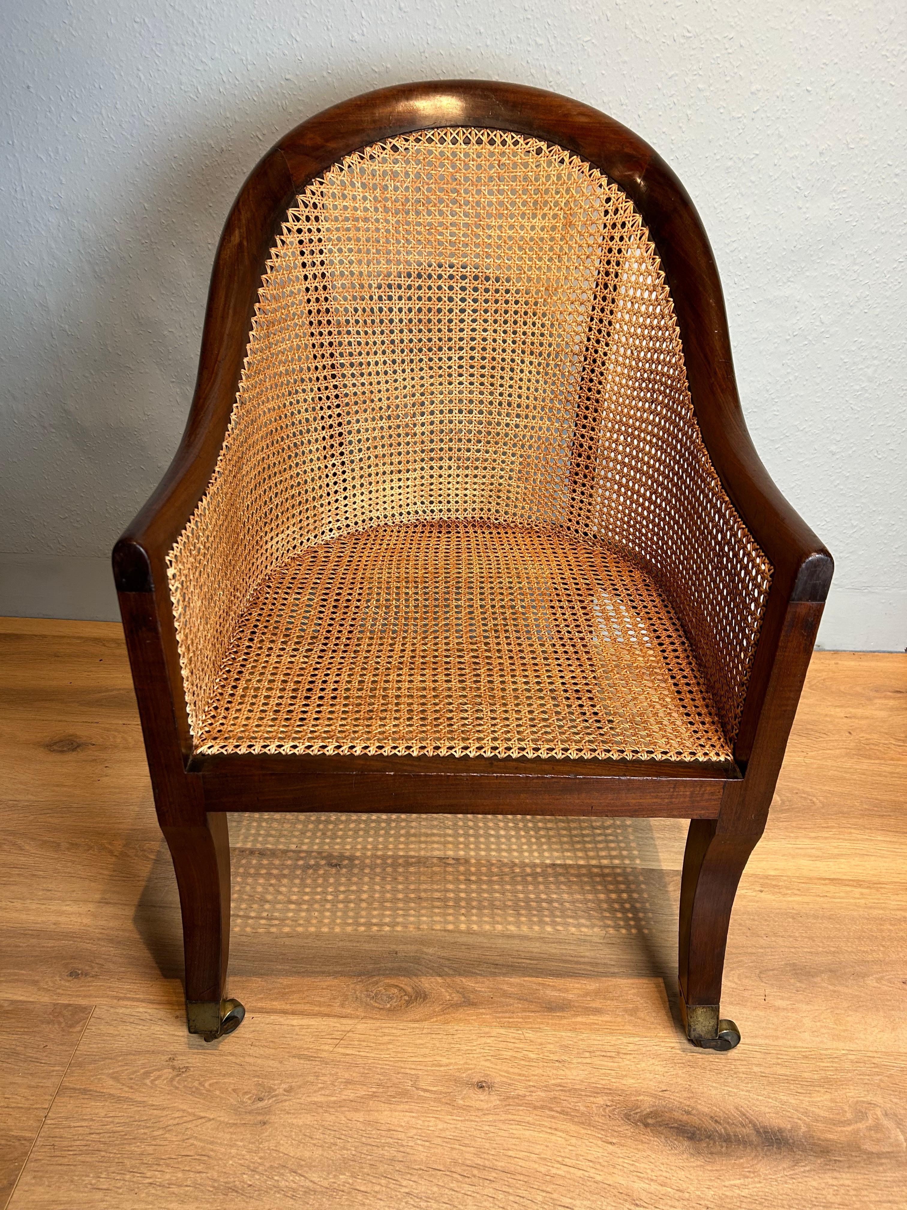 Antique Regency mahogany Bergere arm chair circa 1820 attributed to Gillows in the Roman style. Wonderful flowing shape with elegance, sabre legs to the front and splayed legs to the back ending on quality angled brass castors, ca me work is in