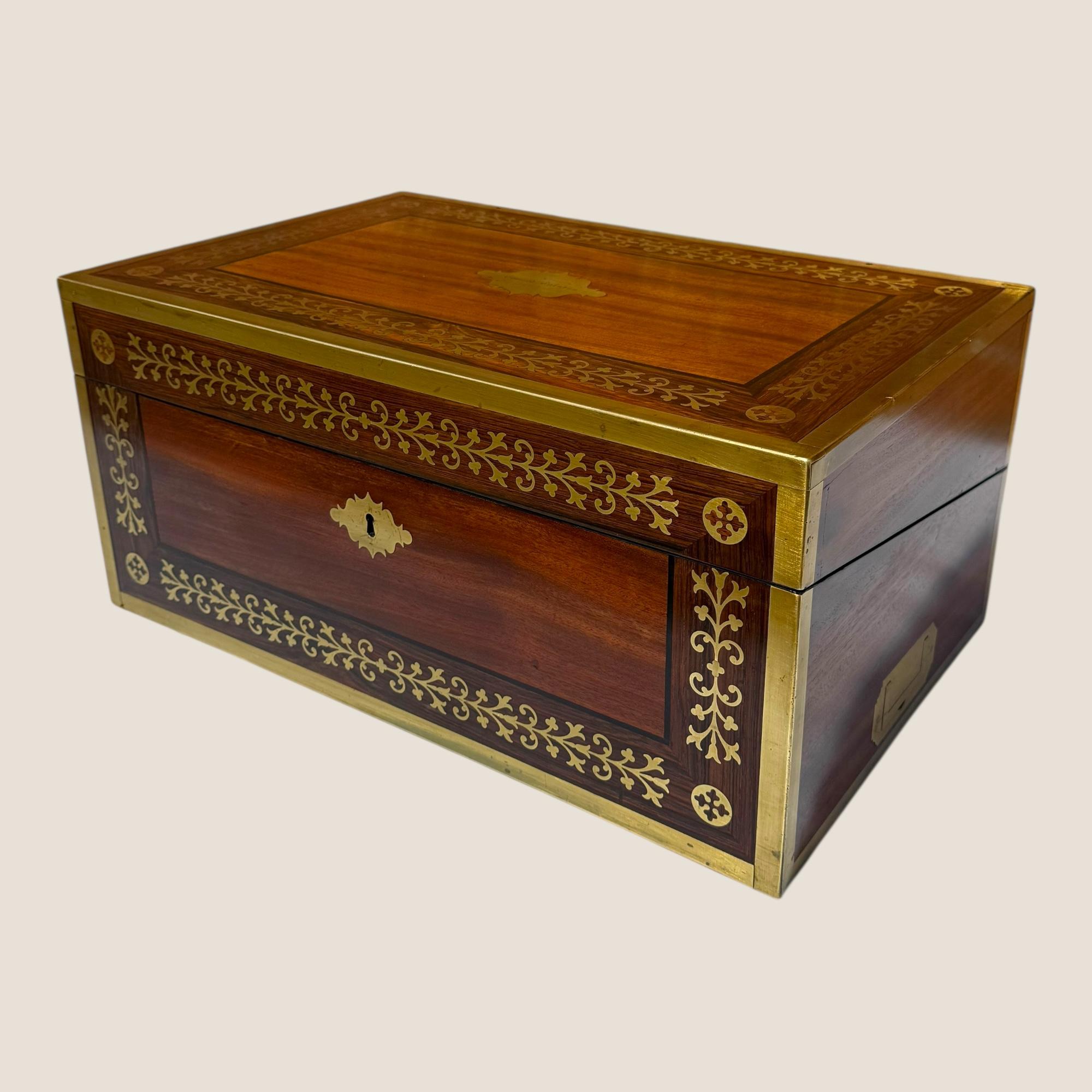Nous avons ici un impressionnant coffret de campagne de style Régence (1811-1820) en acajou et laiton incrusté, avec un tiroir latéral et de multiples compartiments et tiroirs cachés à l'intérieur. L'extérieur de cette boîte est bordé de laiton et