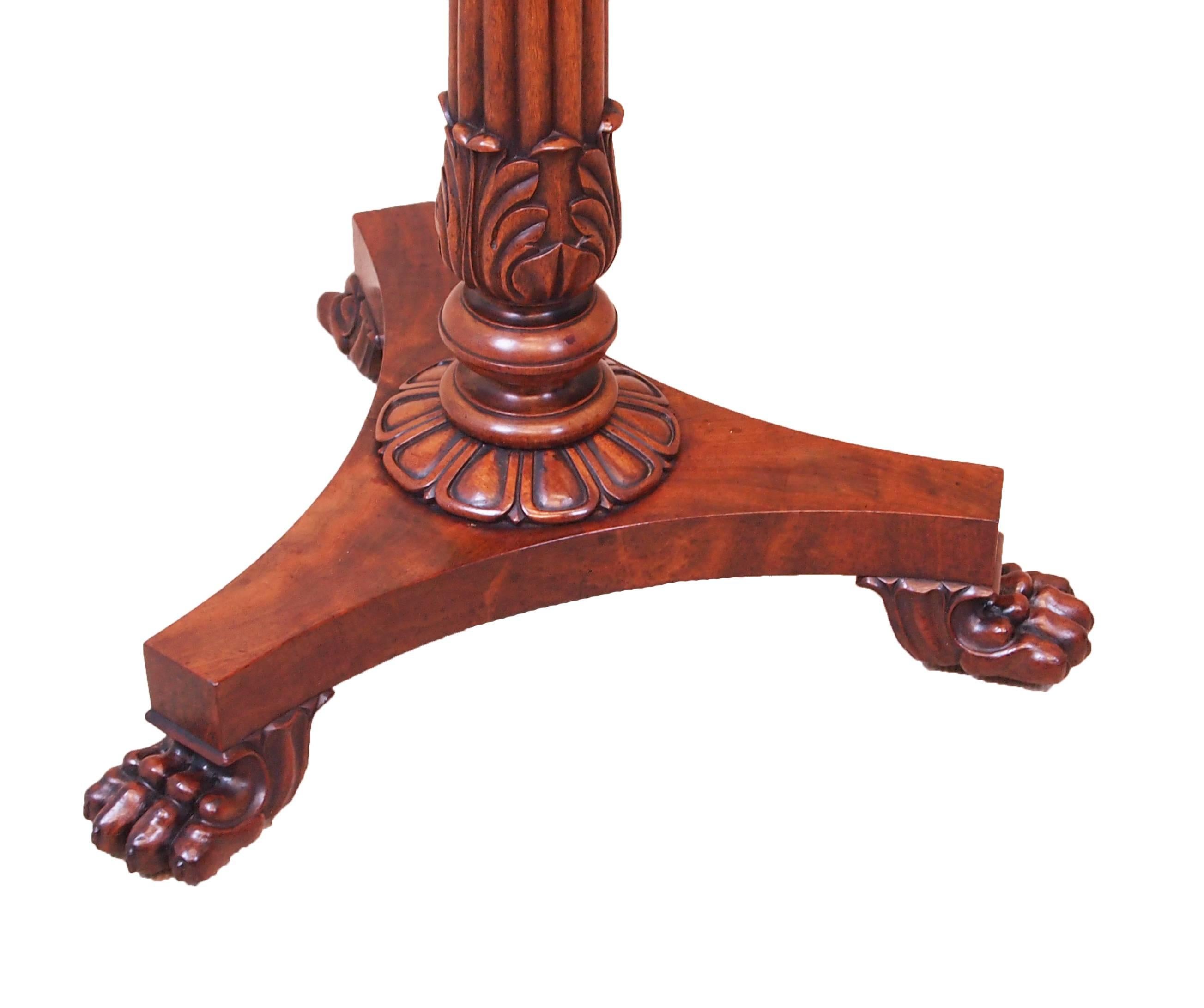 A very good quality Regency period mahogany lamp
table having superbly figured circular segmented tilting
top raised on elegant reeded carved column and
triform base with carved paw feet.