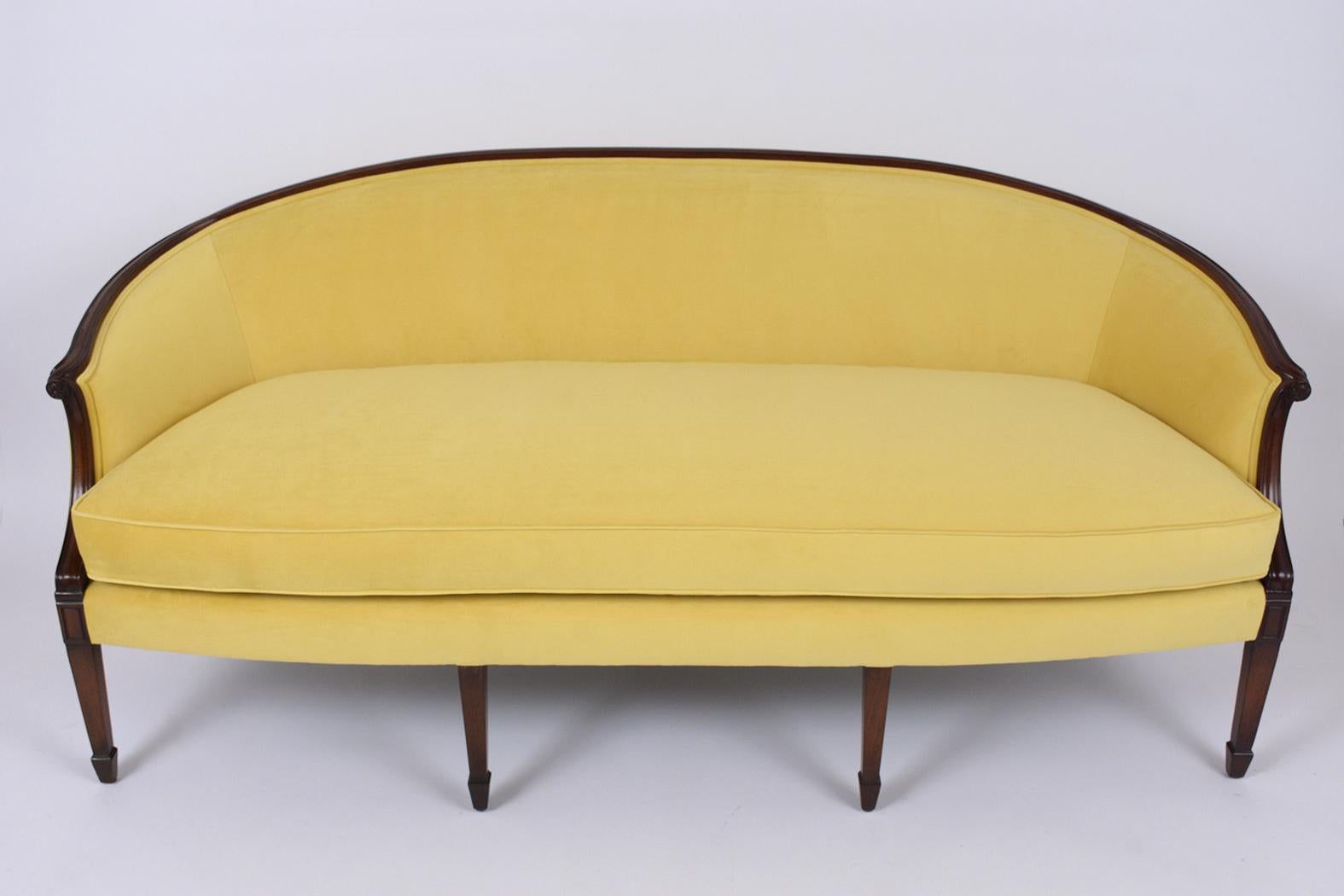 This antique English Regency sofa has been professionally restored and the frame has its original rich mahogany finish with a newly waxed and polished finish. This sofa features a curved back design, scroll arms, and rests on four spadefoot front