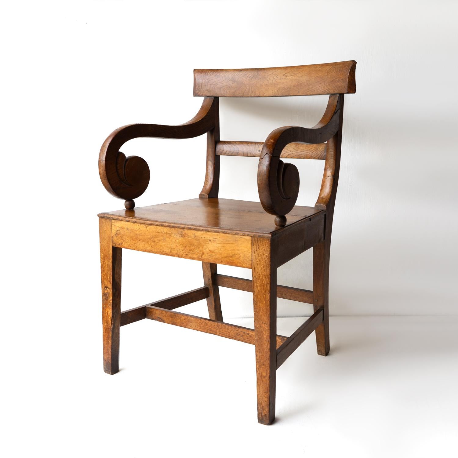 ANTIQUE ELBOW CHAIR 

A handsome and generous chair made from solid oak with peg joints, carved scrolling arms, a shaped backrest, a solid seat and legs united by an ‘H’ stretcher. 

Simple stylish lines with a mix of the elegance of Regency design