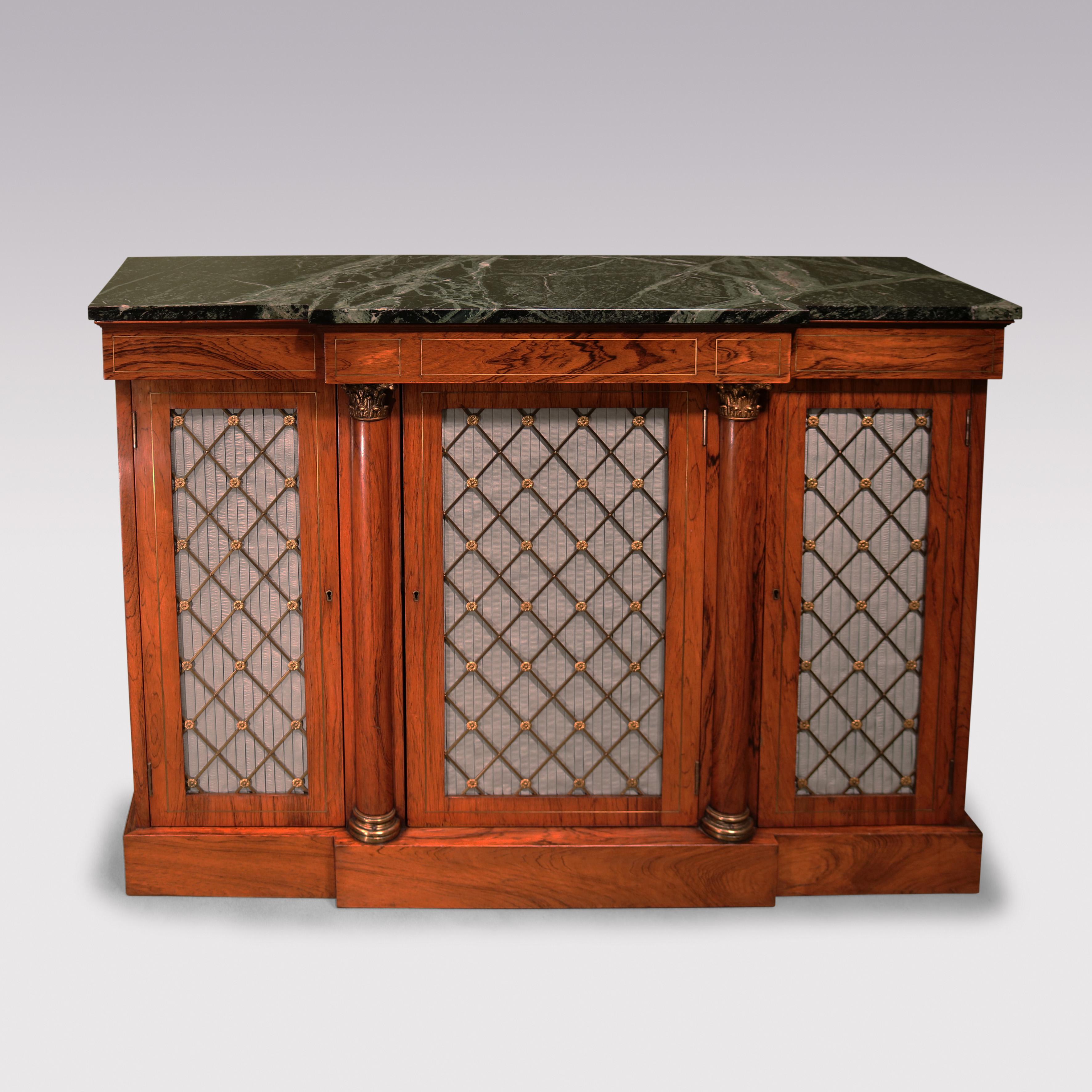 An early 19th century Regency period rosewood breakfront chiffonier, having a green veined marble top above a brass inlaid frieze with three blue silk pleated brass grille doors, flanked by columns with gilt brass capitals, supported on a plinth