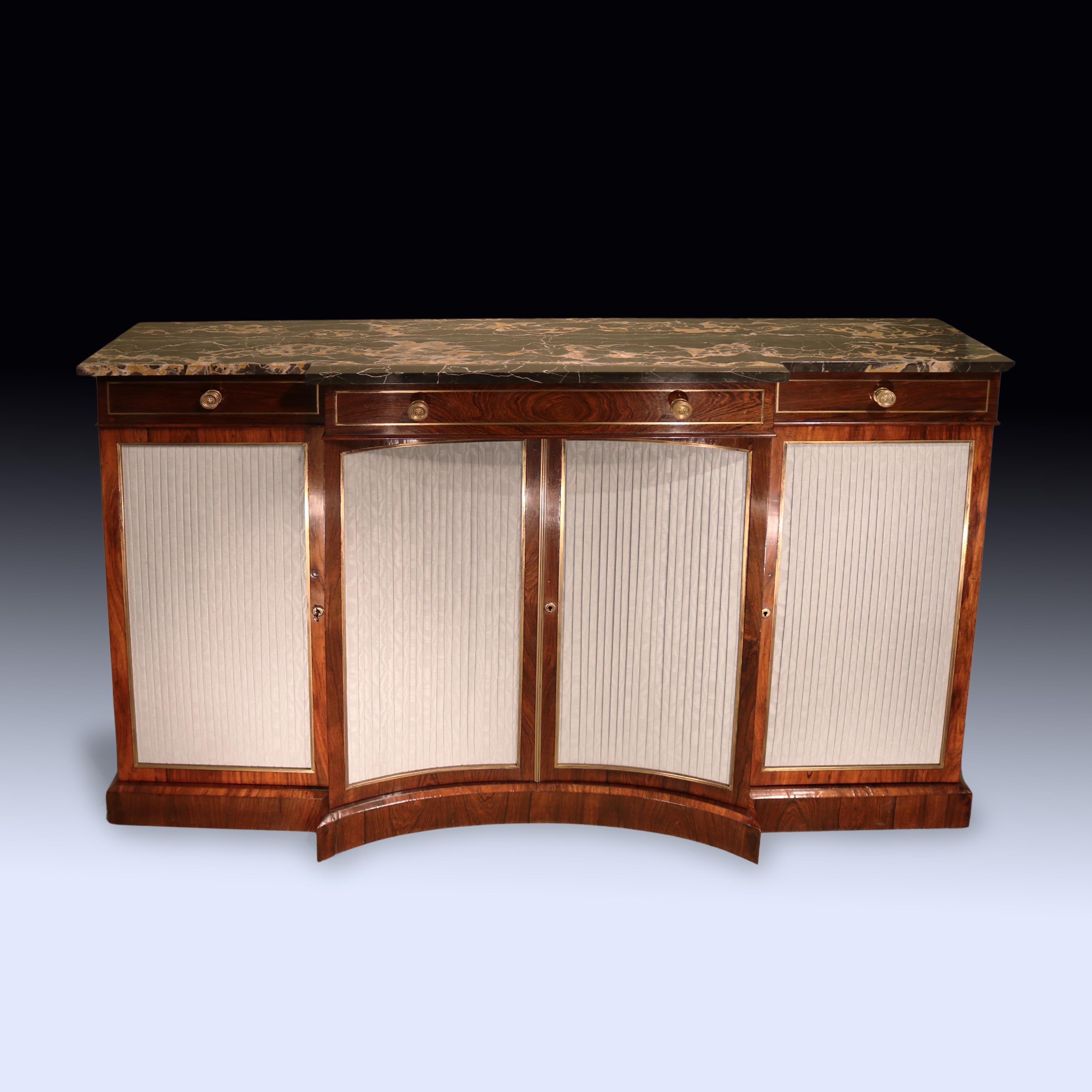 An early 19th Century Regency period rosewood breakfront Chiffonier, having original Diaspro nero e giallo marble top above 3 brass line inlaid frieze drawers.  The Chiffonier, with unusual brass panelled central concave doors flanked by further