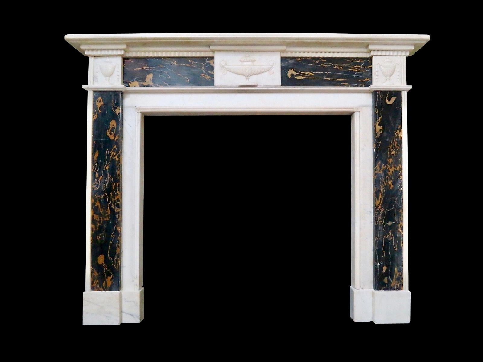 A late Regency fireplace in statuary white and rare black and gold Italian Portoro marble. The jambs with Portoro panels and corner blocks of carved classical urns with bell drops. The centre tablet again of carved classical urn flanked on either