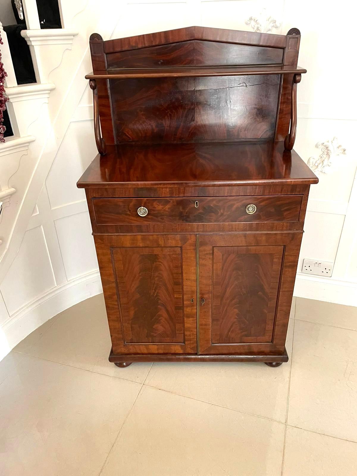 Antique Regency quality figured mahogany chiffonier having a quality figured mahogany back with a single shelf supported by shaped scroll supports above a rectangular shaped mahogany top above one long cutlery drawer. It boasts original brass