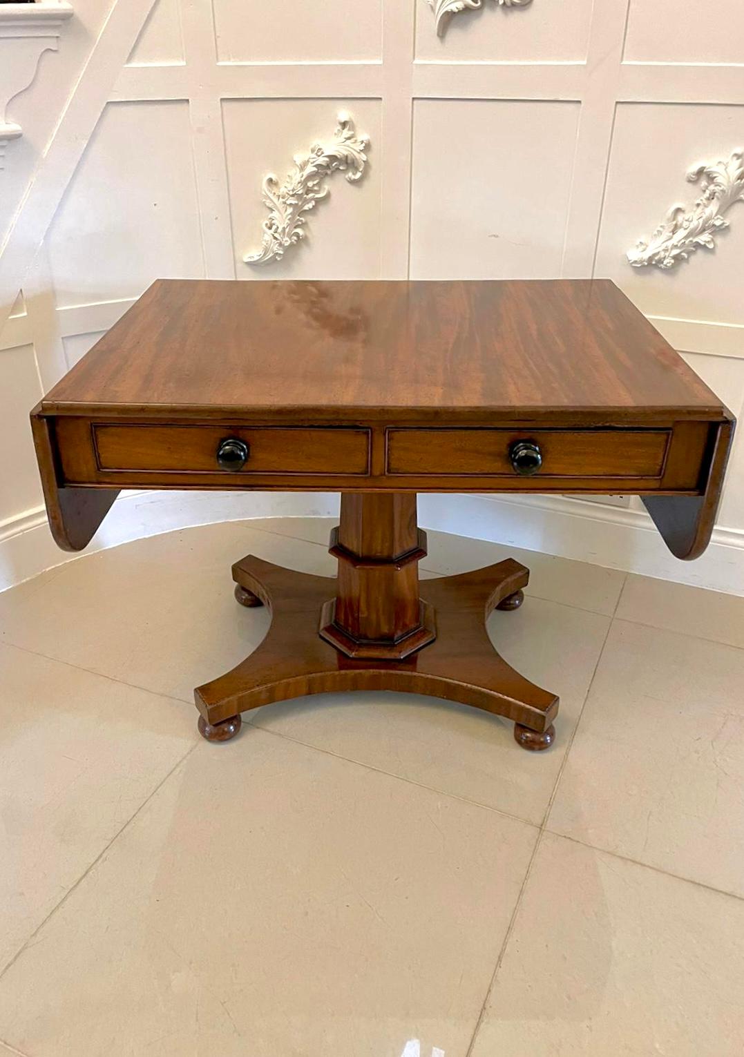 Antique Regency quality figured mahogany freestanding sofa table having a quality figured mahogany top with two drop leaves above two frieze drawers and two dummy drawers with original turned knobs supported by a super hexagonal shaped pedestal