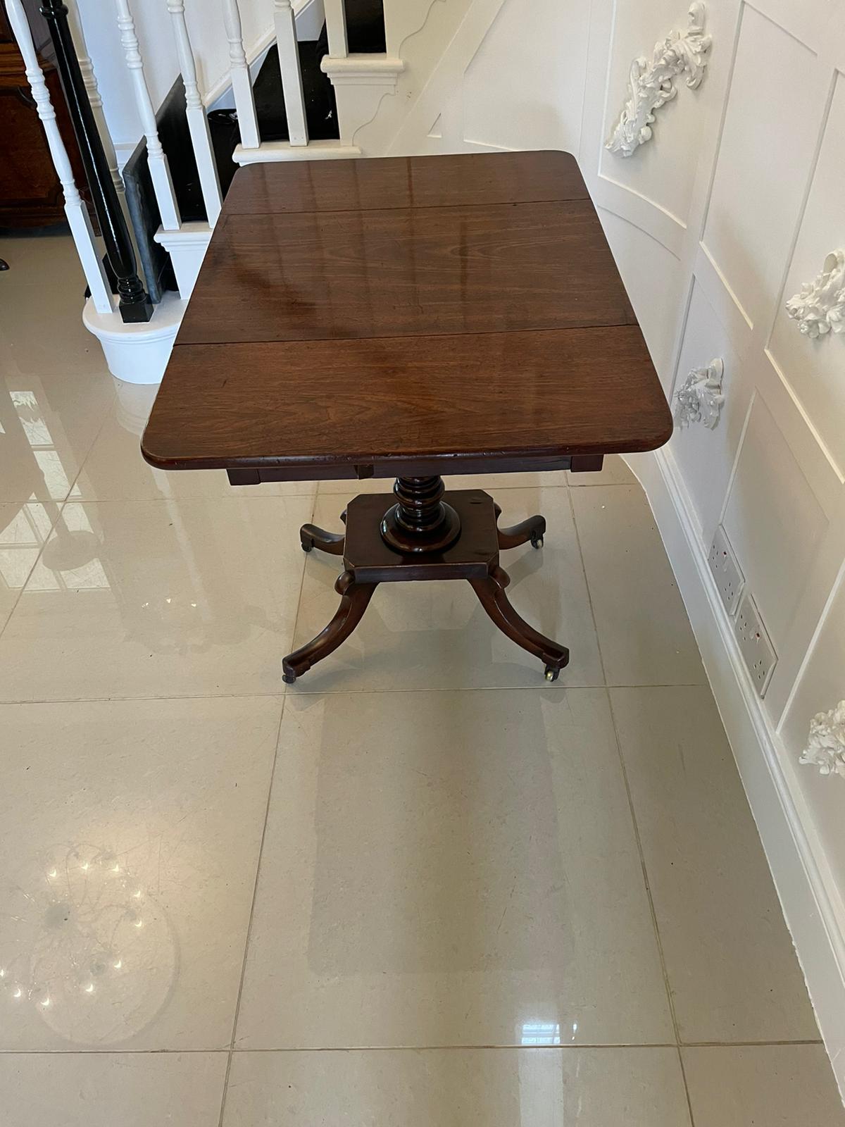 Antique Regency quality mahogany free standing lamp / side table having a quality mahogany top with two drop leaves, drawers to each sides with original turned knobs supported on a turned pedestal column platform base and raised on four shaped sabre