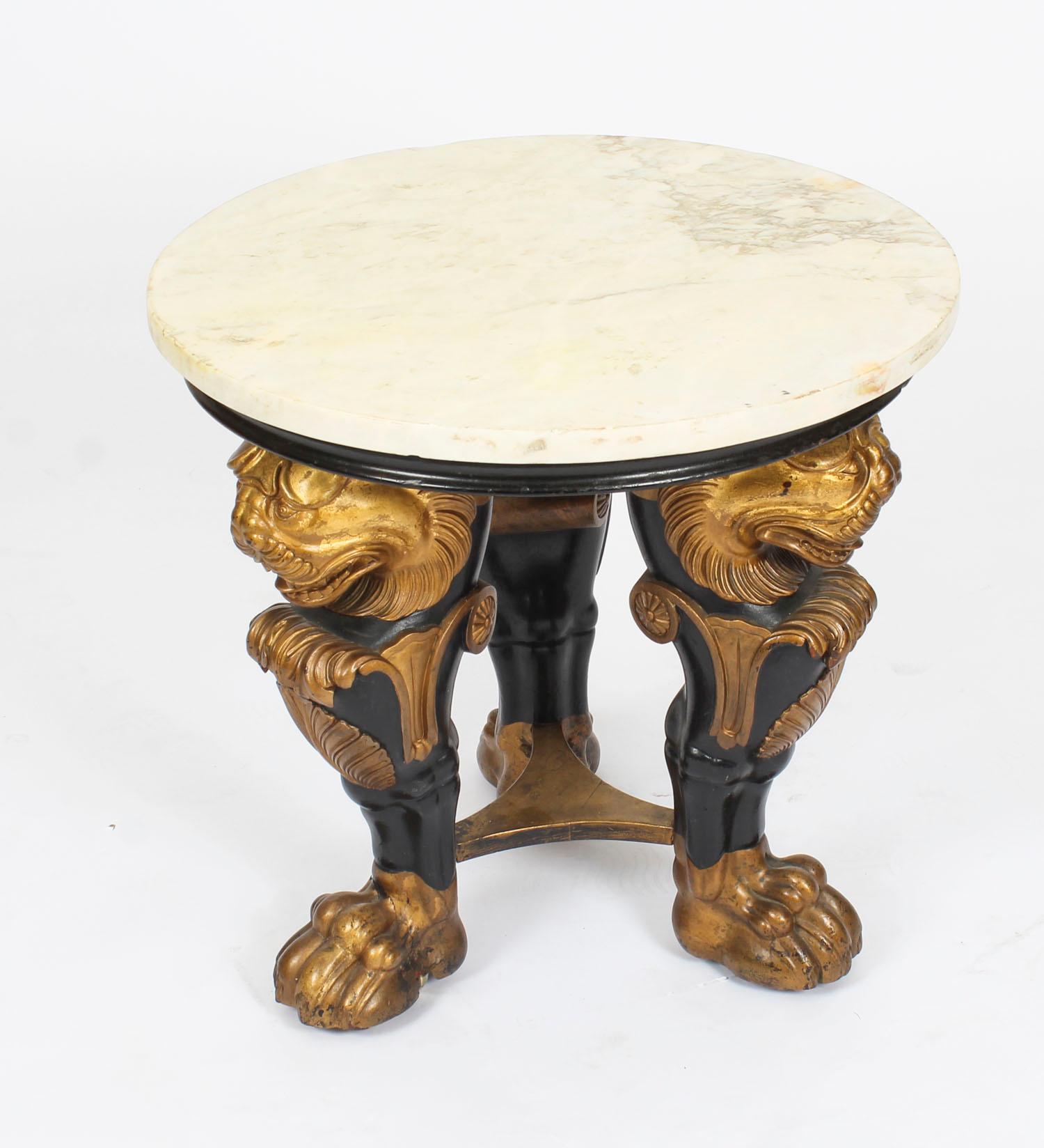 This is a stylish Regency Revival marble topped occasional table with ebonized and gilt decoration, depicting decorative lion's head legs with carved shell and leaf carved knees above lion's paw feet, circa 1880 in date.

Condition:
In excellent