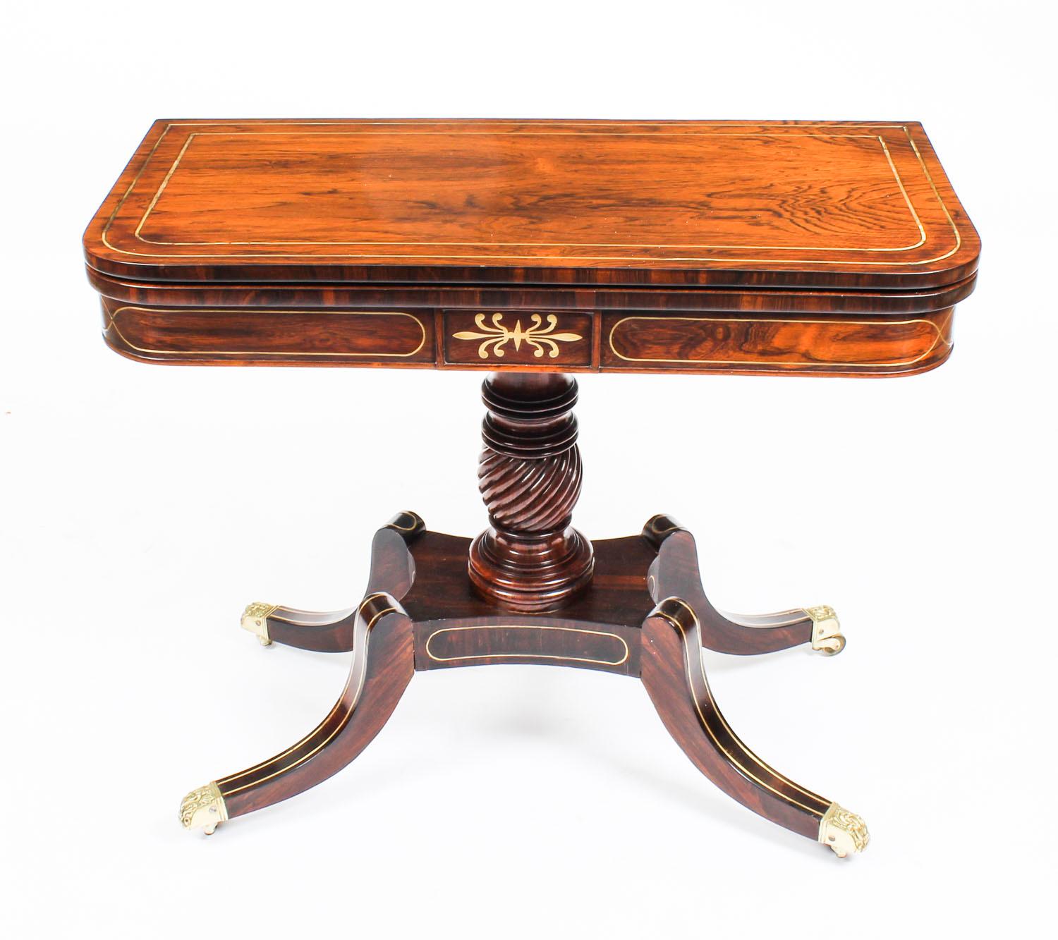 This is a very attractive antique English Regency rosewood and brass inlaid card table, circa 1825 in date.

This rectangular card table is made from beautiful rosewood, the folding top enclosing a green baize lined playing surface. It has
