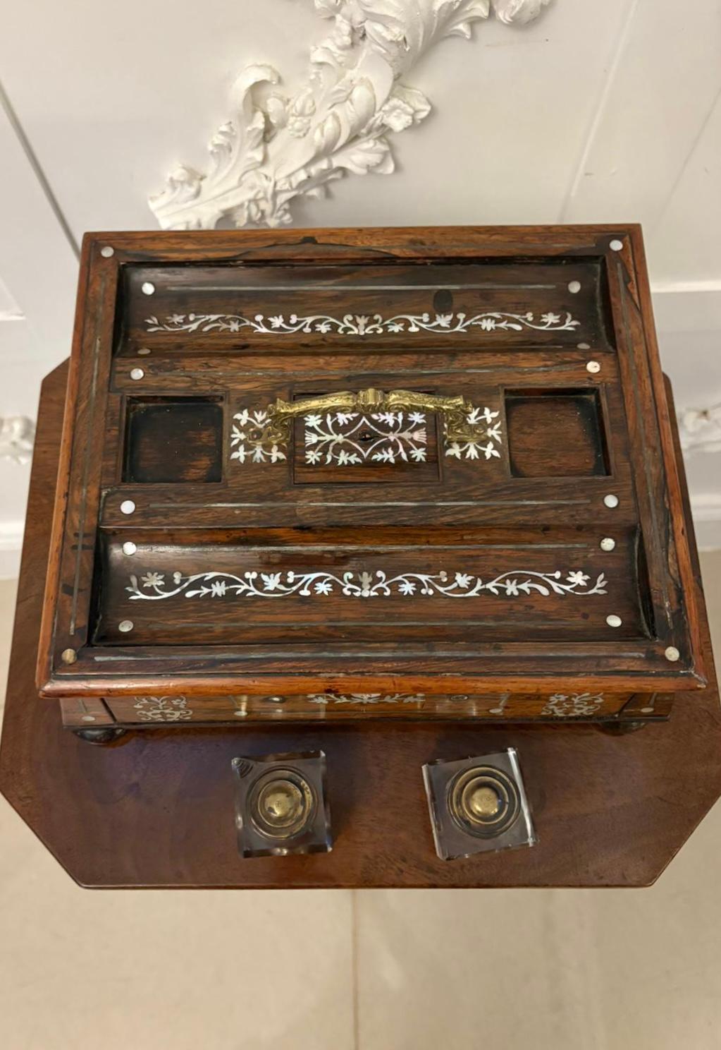 Un raffinato e precoce set da scrivania in legno di palissandro del periodo Regency, splendidamente decorato con un delicato intarsio di madreperla e completo dei calamai originali in vetro tagliato. Questo elegante pezzo da scrivania rappresenta il