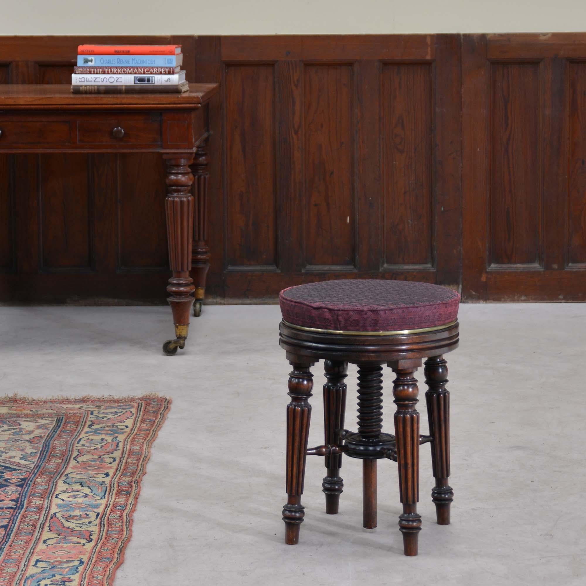 Tabouret de musique en palissandre de style Régence, le plateau circulaire, tapissé de crin de cheval tressé, tourne pour ajuster la hauteur sur une vis, sur des pieds tournés, cannelés et effilés, qui sont réunis par des brancards tournés à un