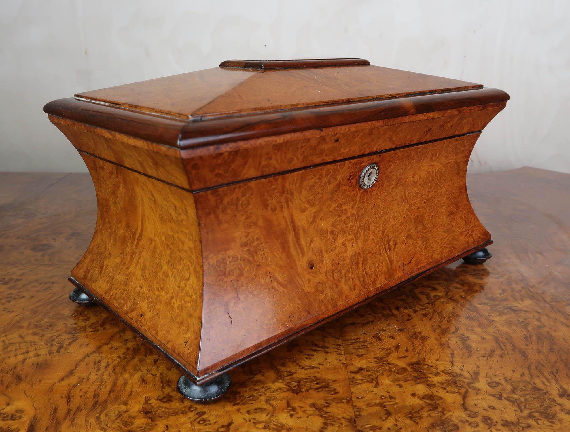 A wonderful Late Georgian or Regency tea caddy. 

Exceptional quality

Fantastic colour and figure in the wood

Tropical hardwood

Lovely sarcophagus shape.

It has a heavy cut glass mixing bowl. I don't believe it is the original one.

No Key

Free
