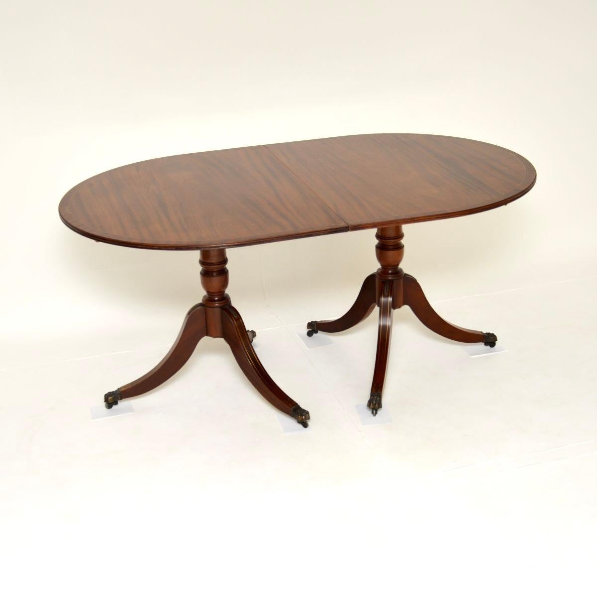 Un delizioso tavolo da pranzo allungabile in ottone intarsiato in stile Regency. Prodotto in Inghilterra, risale agli anni '1930 circa.

Ha un bellissimo piano con bordi in ottone intarsiato e bordi a fasce incrociate. Ogni metà poggia su una base a