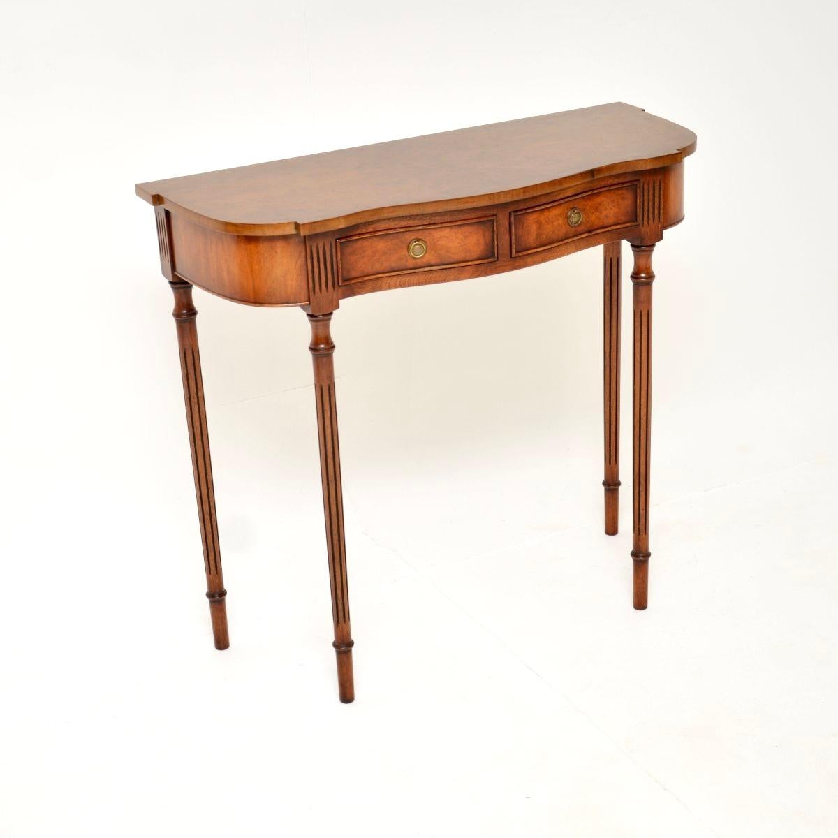 A beautiful and elegant antique Regency style burr walnut console table. This was made in England, it dates from around the 1950’s period.

The quality is excellent and this has a lovely, compact and stylish design. The front has a serpentine shape,