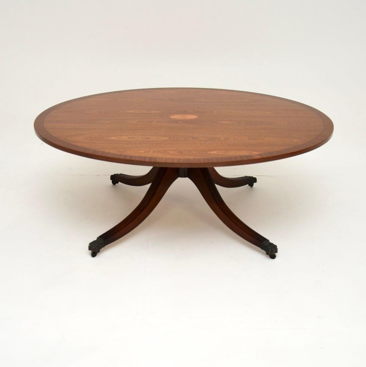 A large and impressive antique coffee table in the Regency style. This was made in England, it dates from around the 1960’s.

The quality is outstanding, the large oval top has stunning inlays of satinwood. It also has a finely cross banded