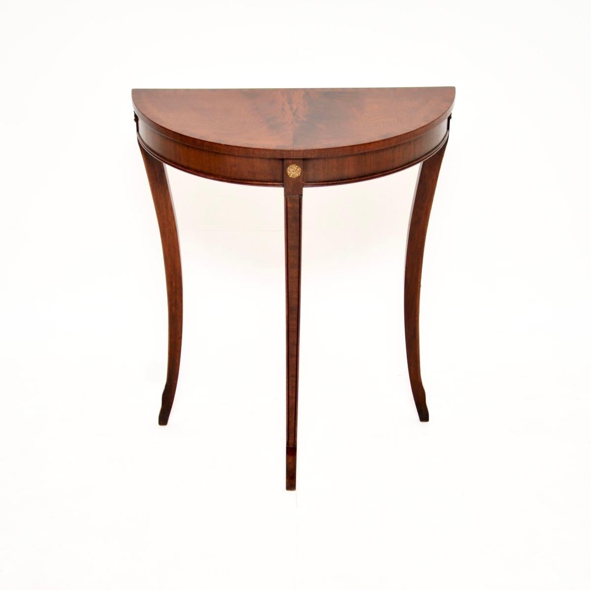 Un bellissimo ed elegante tavolo consolle antico in stile Regency. Prodotto in Inghilterra, risale agli anni '1950 circa.

La qualità è ottima, il formato è molto utile e piccolo. Le tre gambe hanno un bellissimo design a sciabola e sostengono un