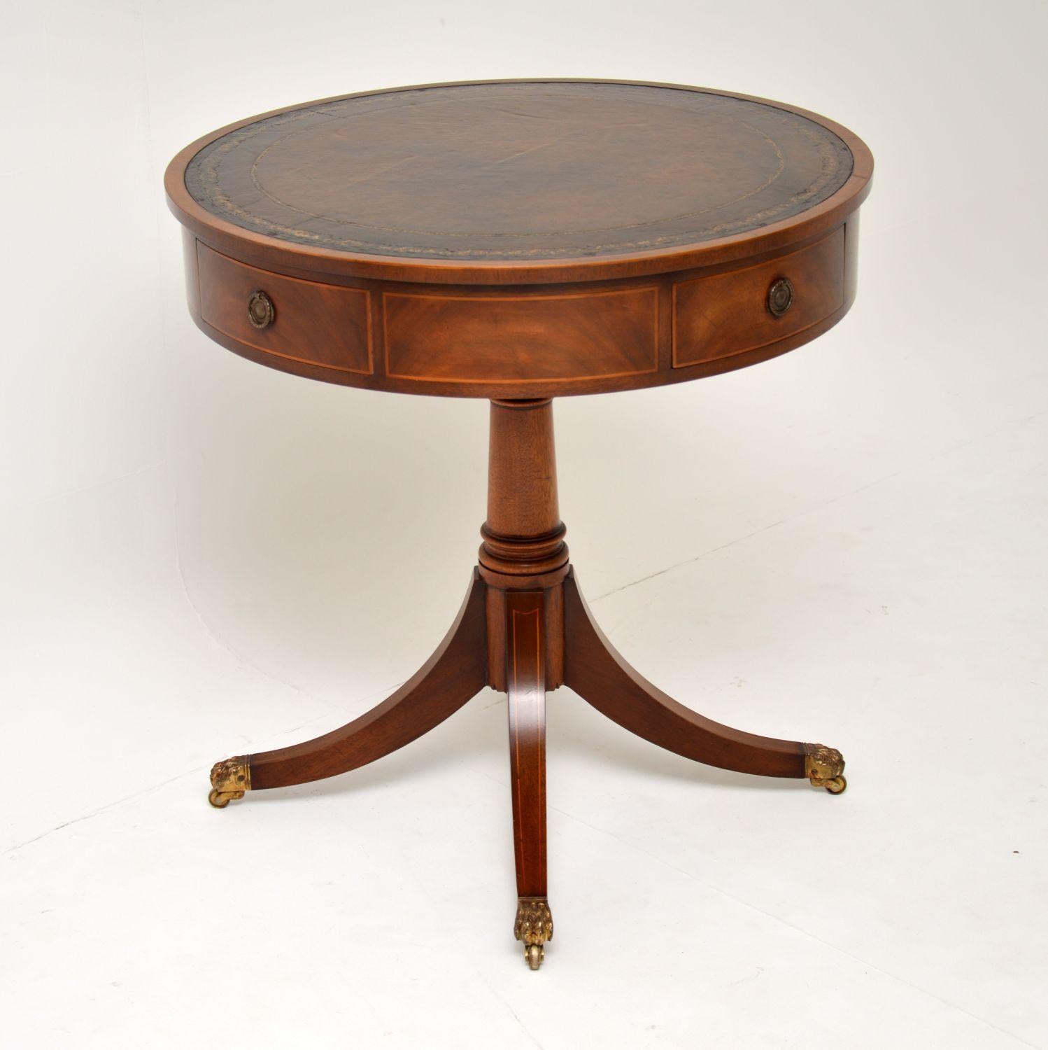 A smart and fine quality antique drum table in the Regency style. It’s beautifully made from mahogany, with satinwood inlays and a well tooled segmented leather top.

This dates from the 1920s-1930s, it is in excellent condition for its age, we