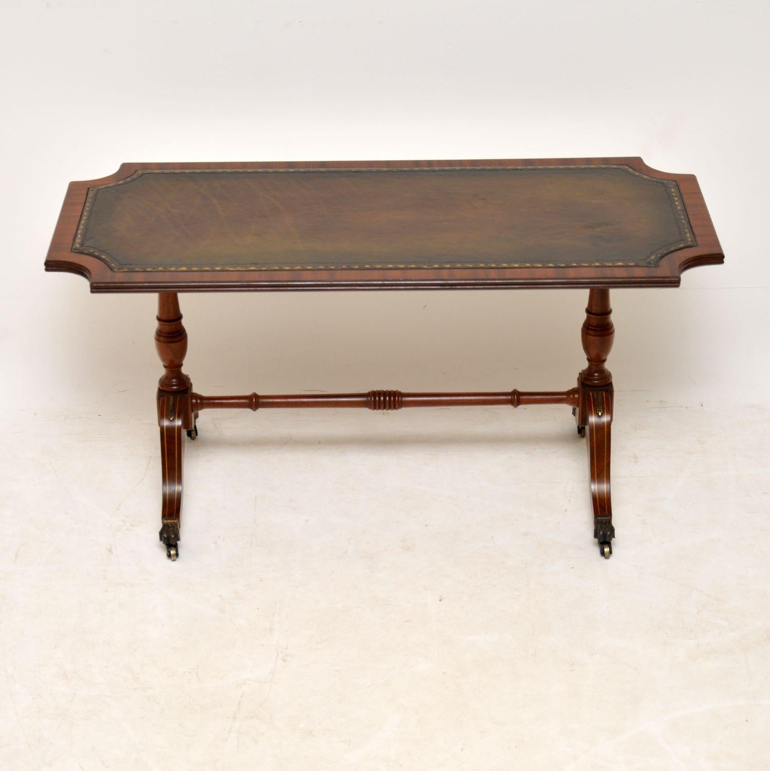 Antique Regency style mahogany leather top coffee table in excellent condition and dating from circa 1950s period.

It has a tooled leather and a reeded top edge. This sits on twin baluster pedestals which have sabre legs below and brass claw