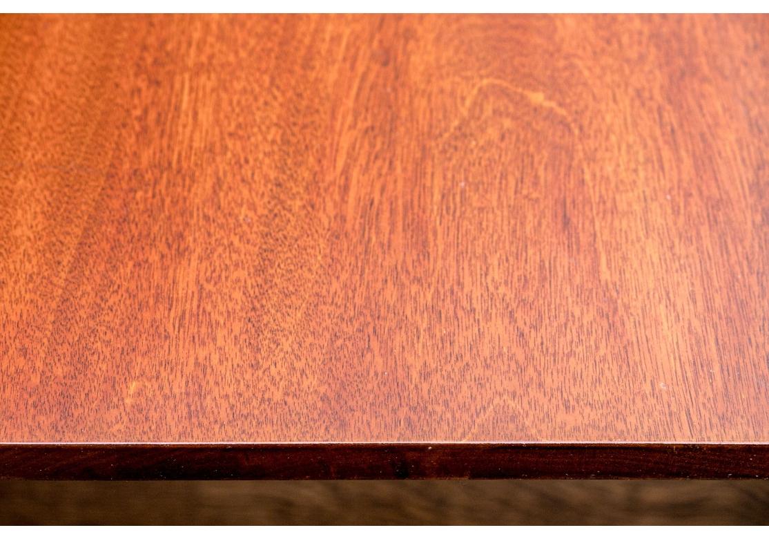 Table de salle à manger ovale en acajou de style Régence avec double piédestal et deux abattants. La table à pieds cylindriques repose sur des pieds en forme d'araignée avec des capuchons et des roulettes en laiton. La table est livrée avec deux