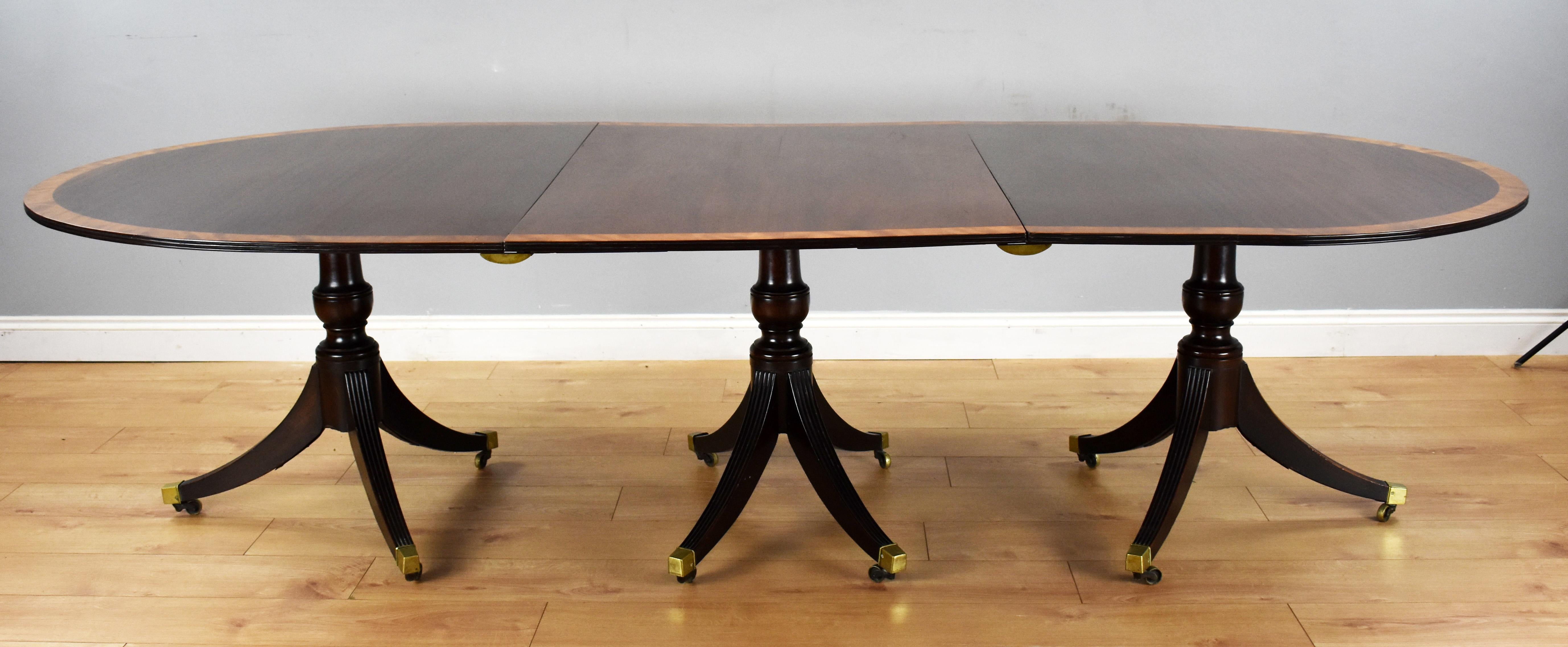 For sale is a good quality Regency style solid mahogany pedestal dining table, having three pedestals and additional leaves, the top has a nicely banded edge surrounding well figured timber. Standing on elegant splayed legs terminating on brass