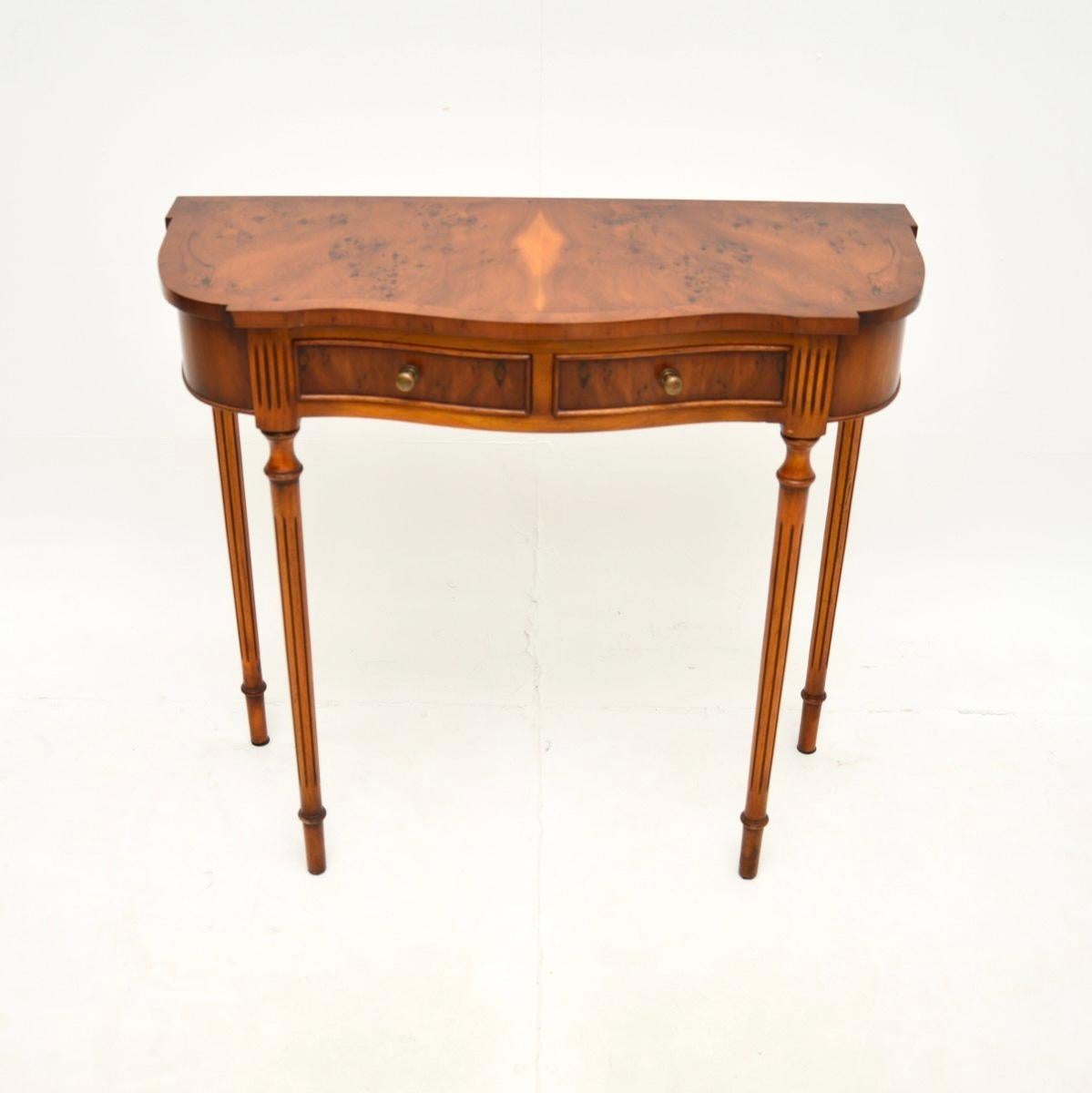 A fine and elegant antique Regency style yew wood console table. This was made in England, it dates from around the 1950’s.

It is beautifully made, with a serpentine shaped top that has cross banded edges. The drawers have solid brass handles, this