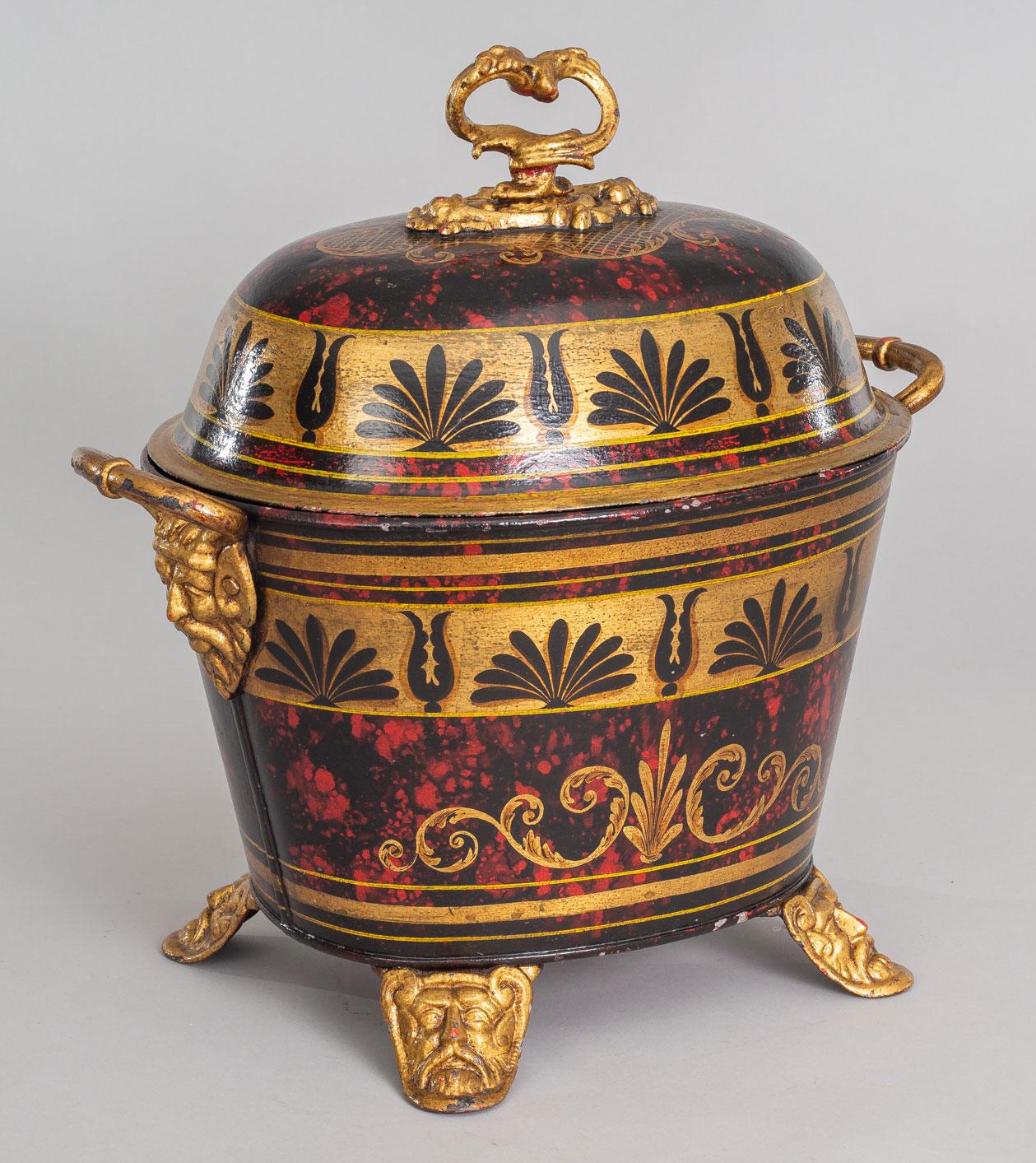 A late Regency toleware oval coal scuttle and cover decorated with wide gilded bands painted with black stylized acanthus leaves on a striking mottled red and black tortoiseshell-like background, the gilded handles and feet with Norse head masks,