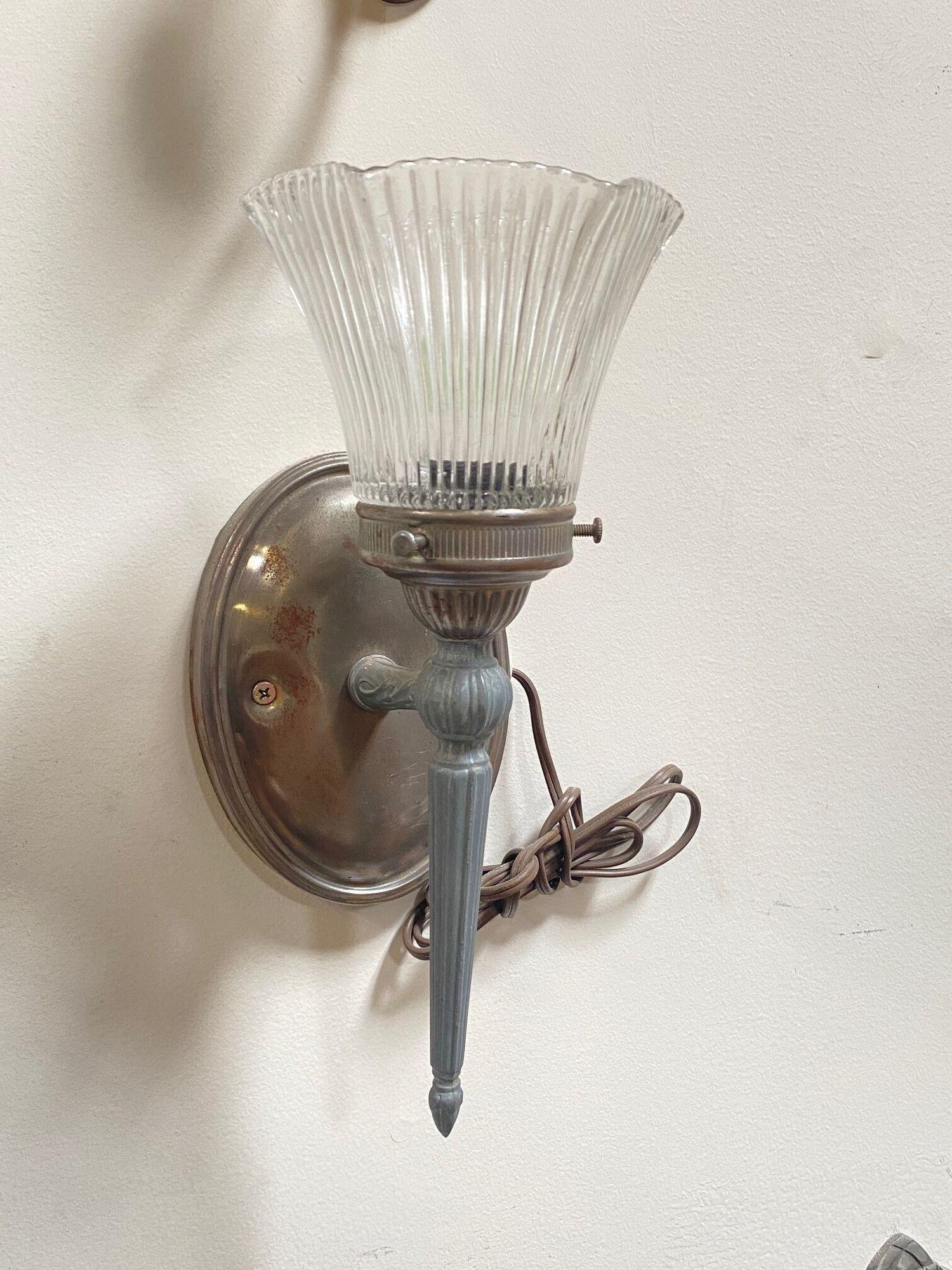 Antique regency speleter metal electric wall sconce with ripped glass globe. This torchiere-style scone features a touch fixed with ripped tulip glass shade fixed to an oval wall plate.

1920, United States
