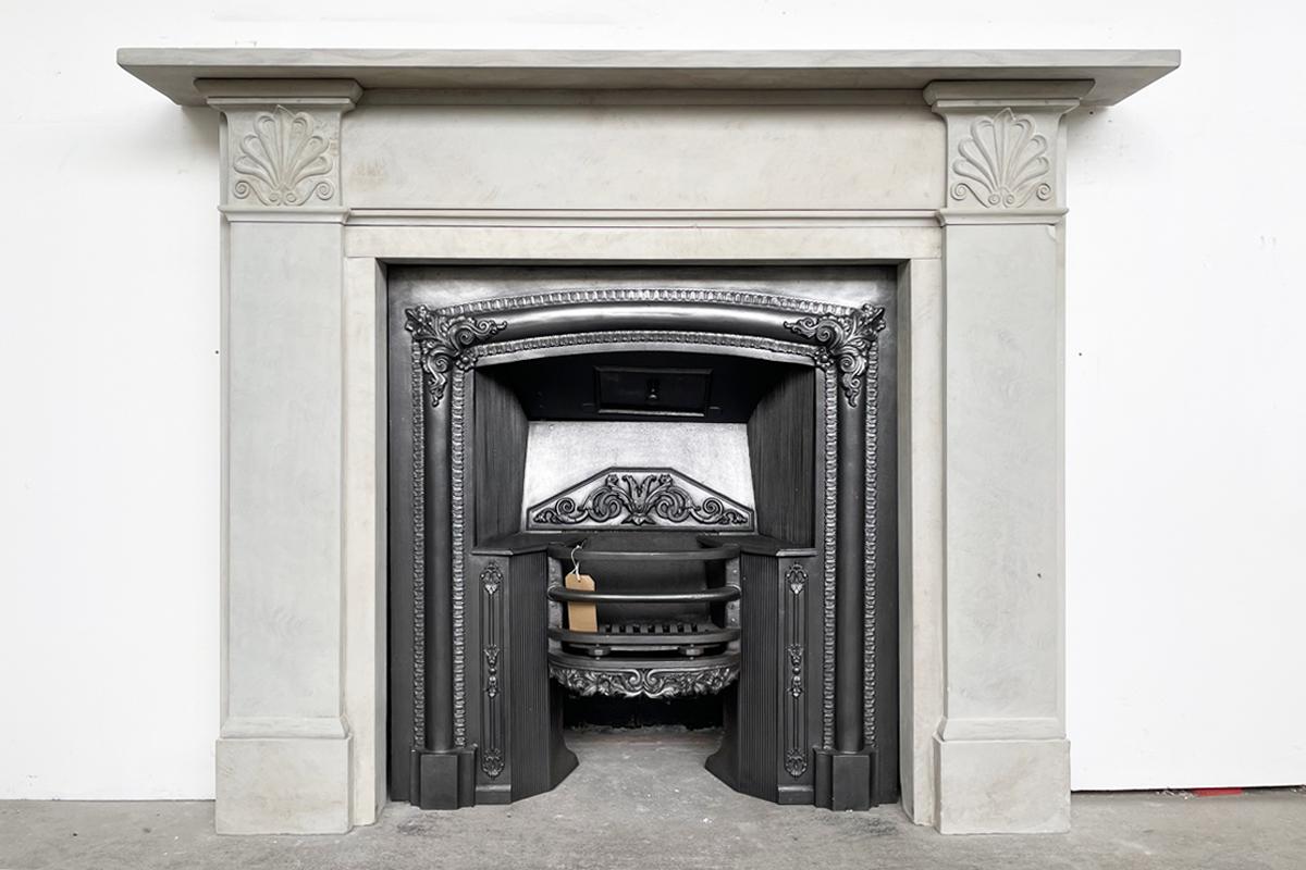 Antique early 19th century Regency grey York stone fire surround with finely anthemion carved capitals.

For detailed sizes please see the size diagram within the image gallery

Pictured with an antique fire grate, sold separately.

We