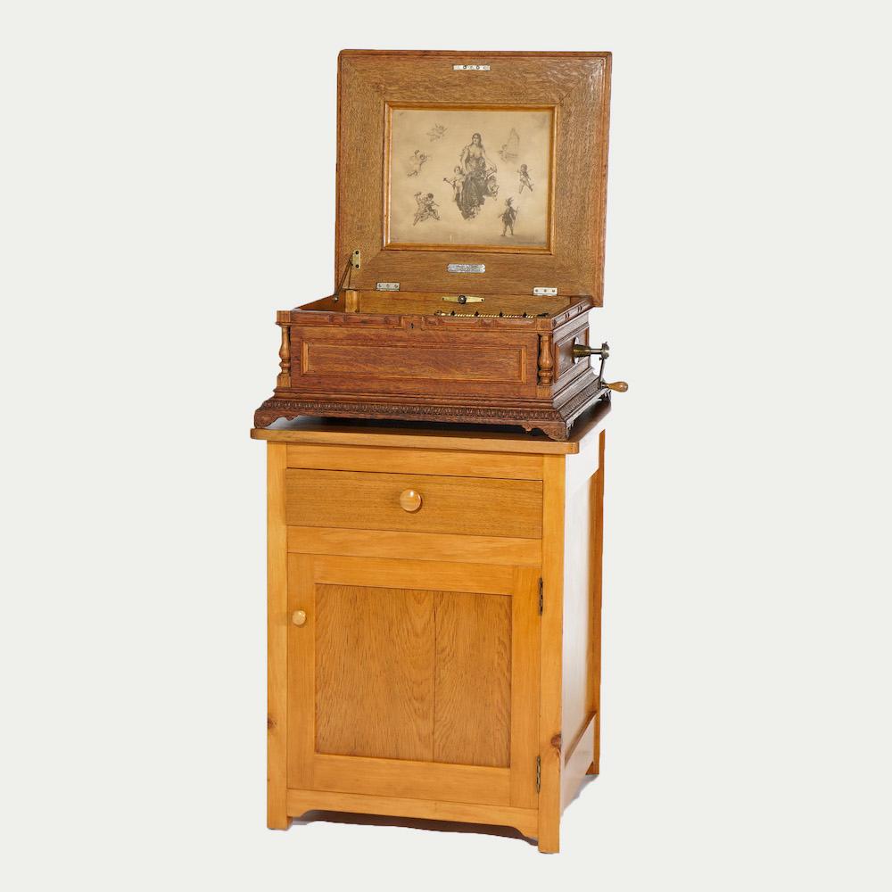 An antique Regina music box offers carved oak case with turned corner column and raised on bracket feet, maker label and number as photographed, c1890; newer custom floor cabinet with upper drawer and lower single drawer discs included. 
Measures-