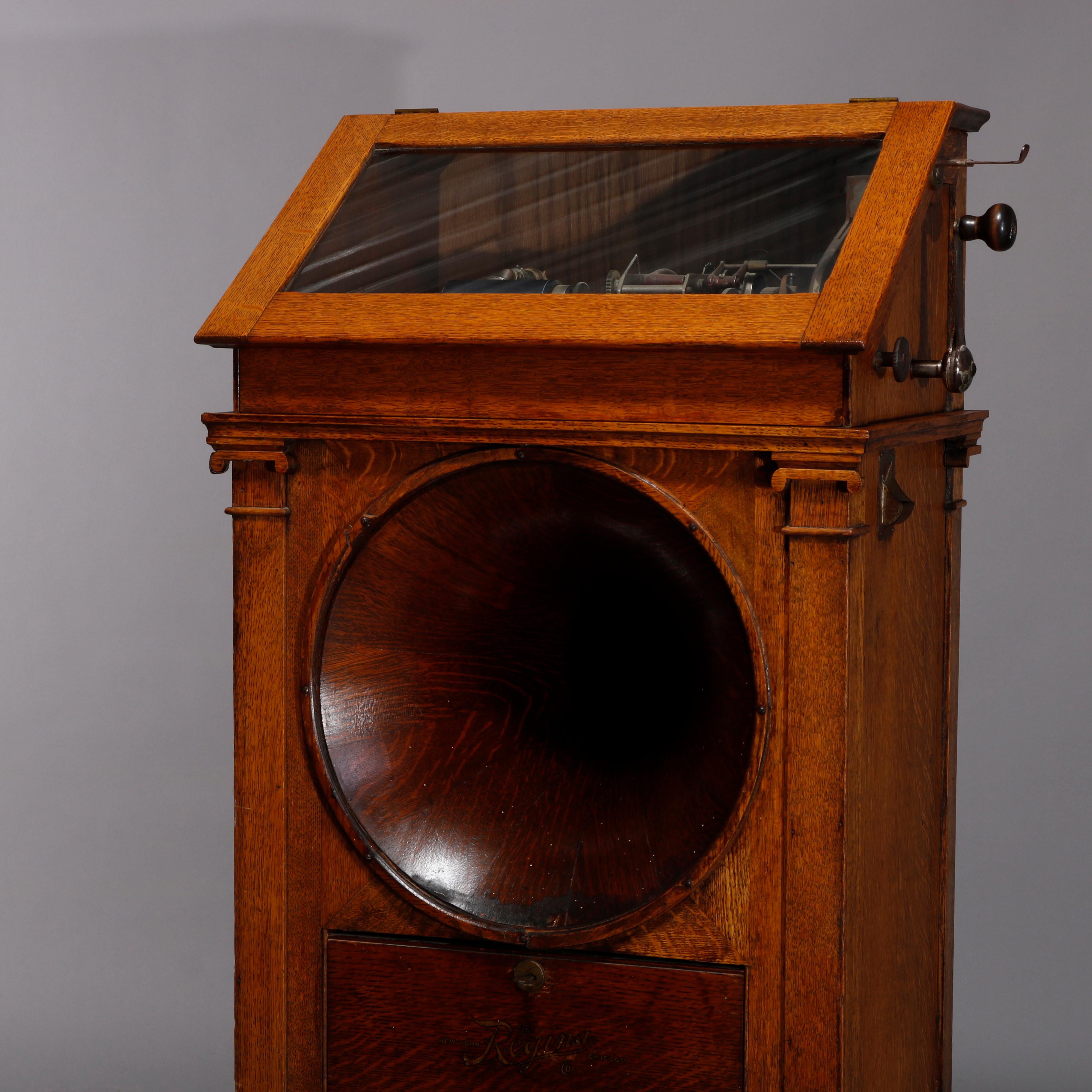 An antique Regina hexaphone coin operated cylinder music box offers floor model case with upper glass slant front observation door opening to player surmounting case with central speaker and flanking carved Corinthian column supports, nickel